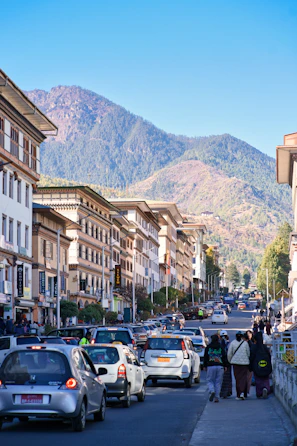 Busy street with cars and buildings against mountains
