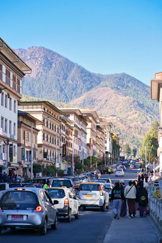 Busy street with cars and buildings against mountains