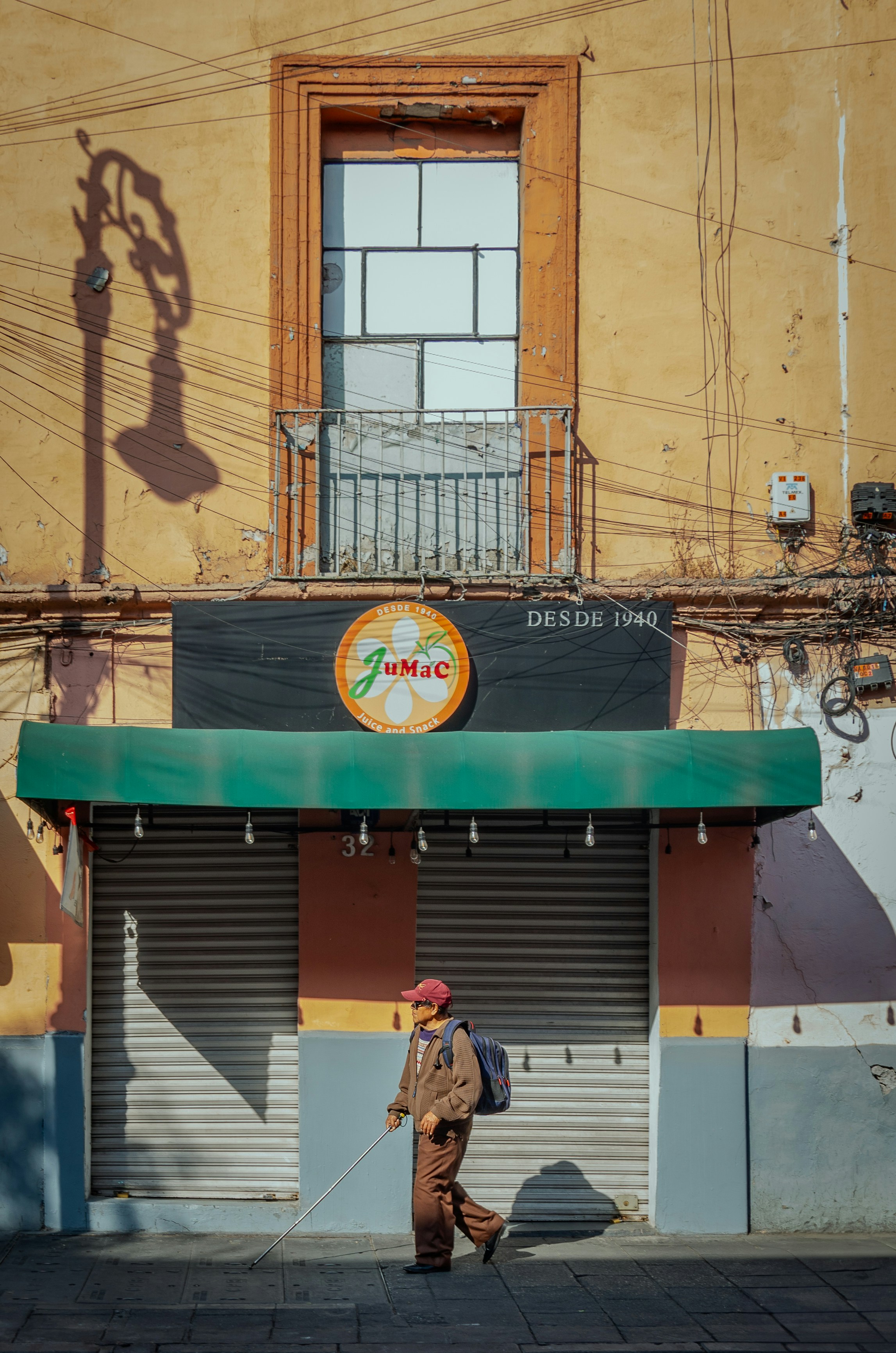 Man with cane walks past closed storefront