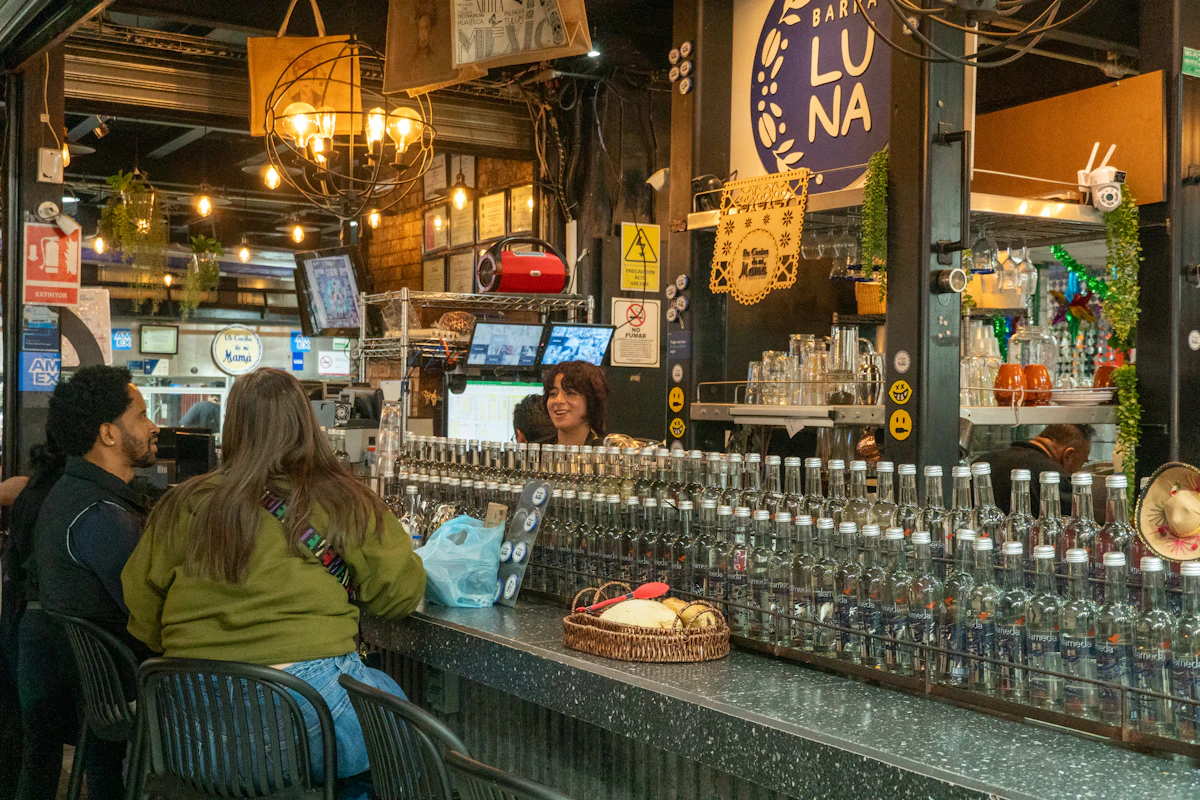 People sitting at a Mexico City bar with bottles behind the counter