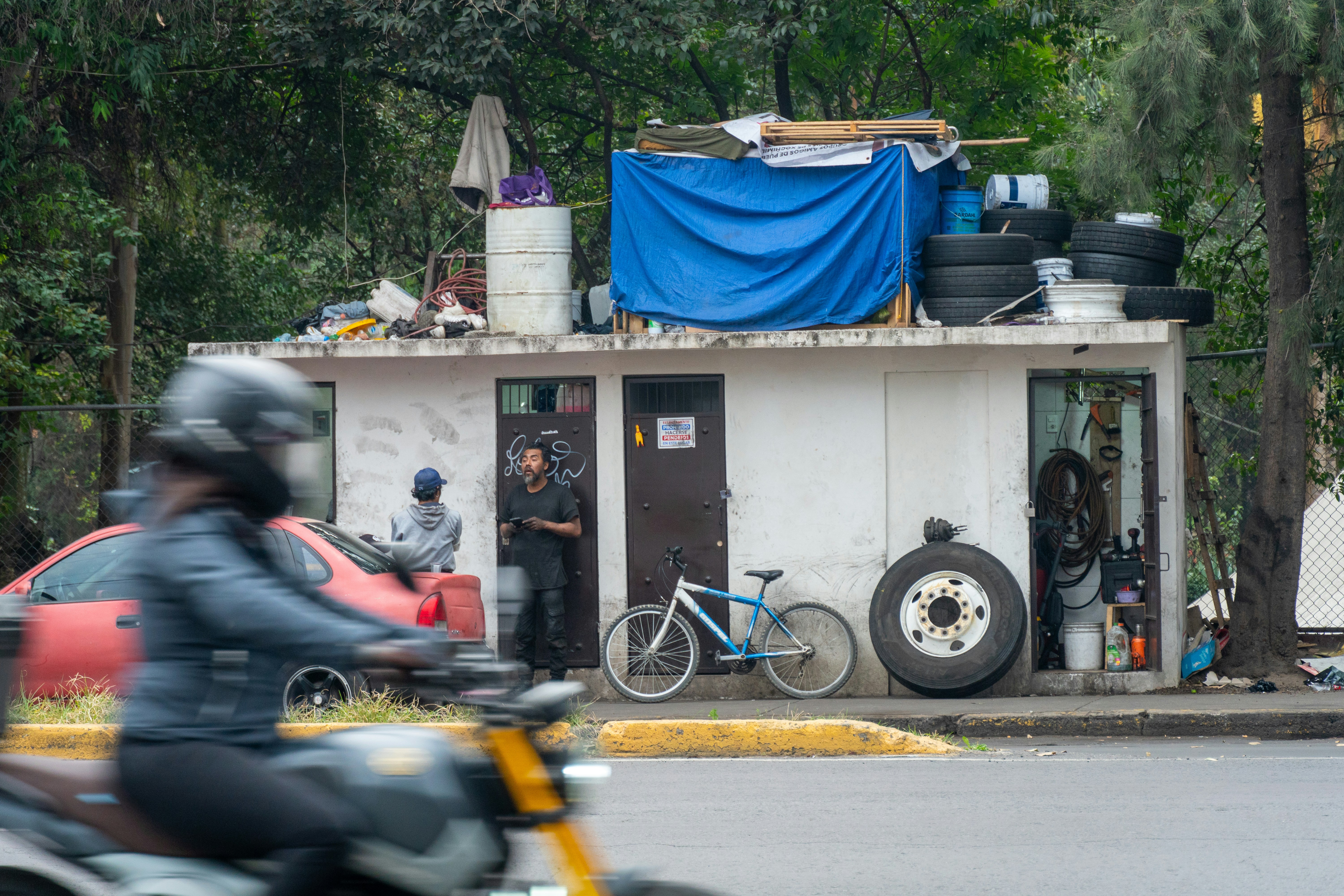 Pequeña estructura improvisada con neumáticos y lona azul.