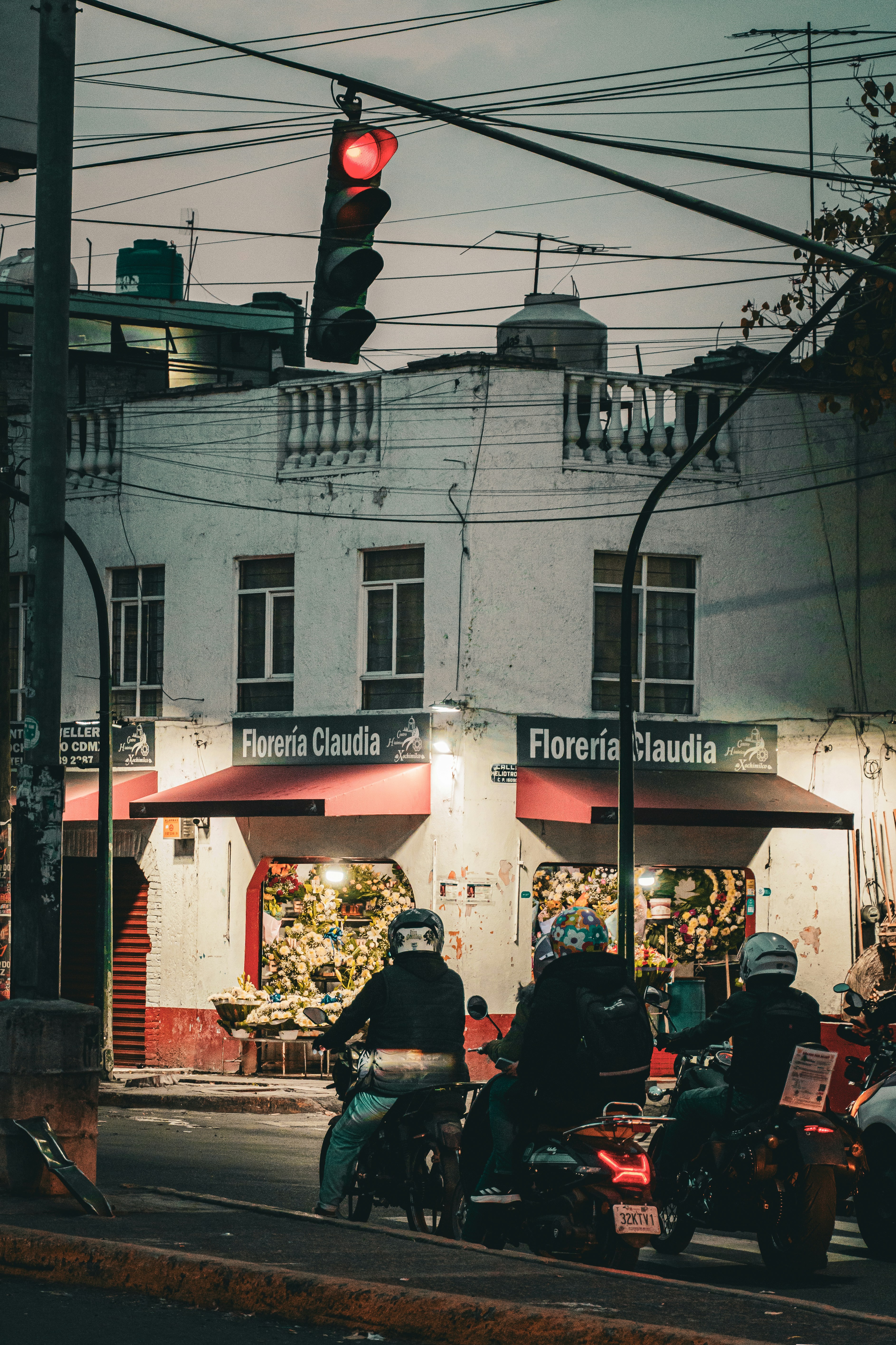 Three motorcyclists wait at a red traffic light.