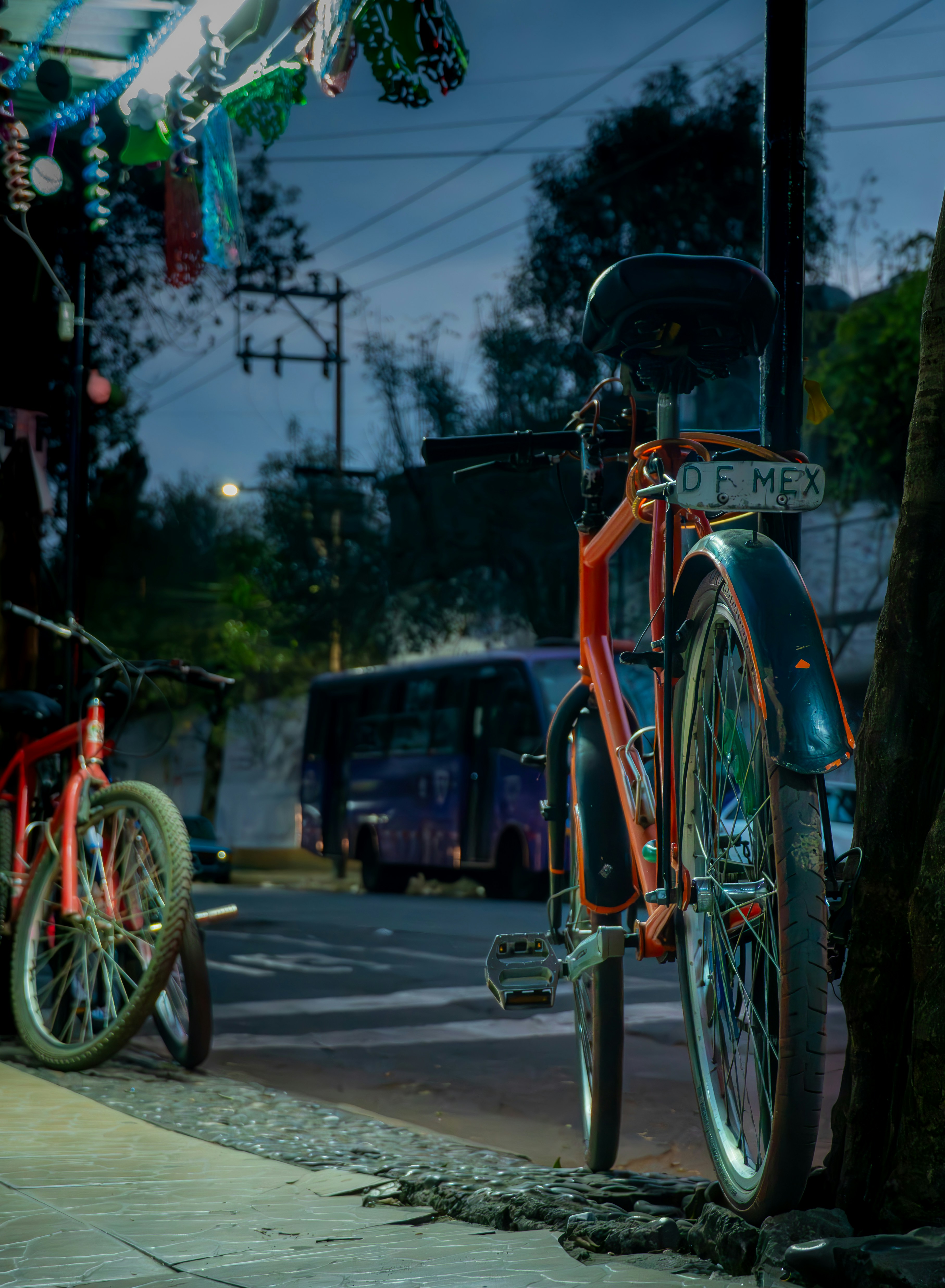 Two bicycles parked on a street at dusk.