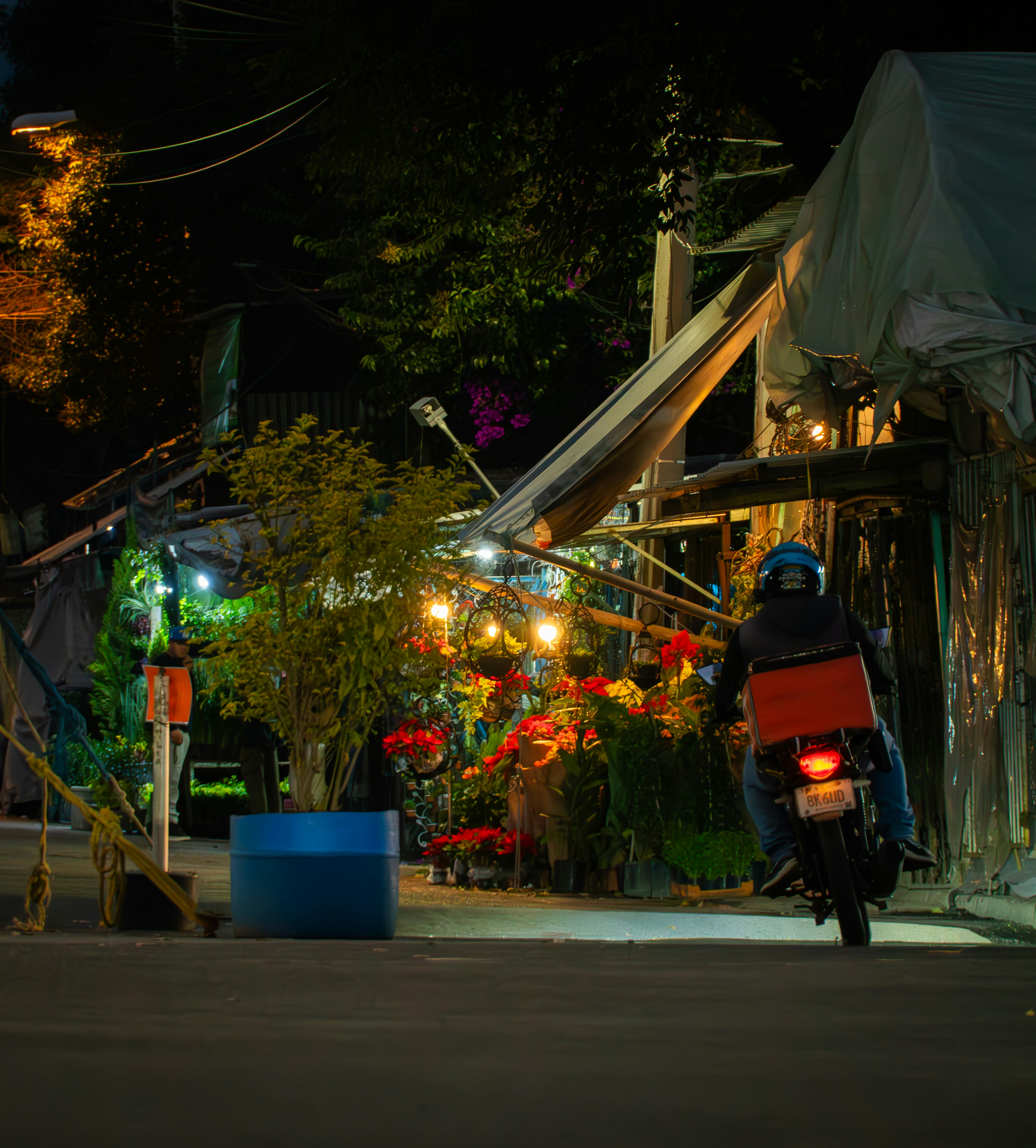 Delivery person on motorcycle at night near flowers