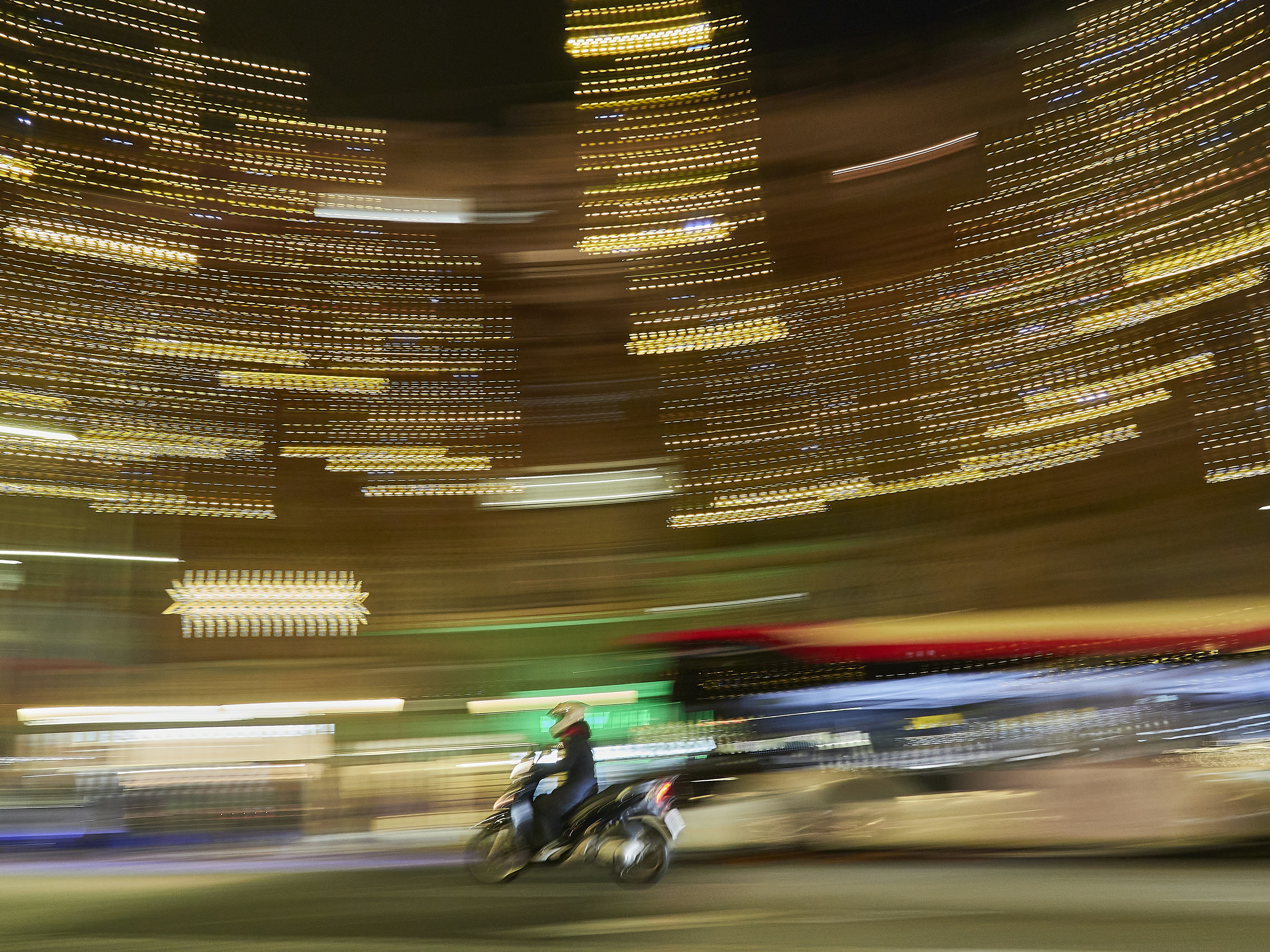 Motorcyclist riding through blurred city lights at night