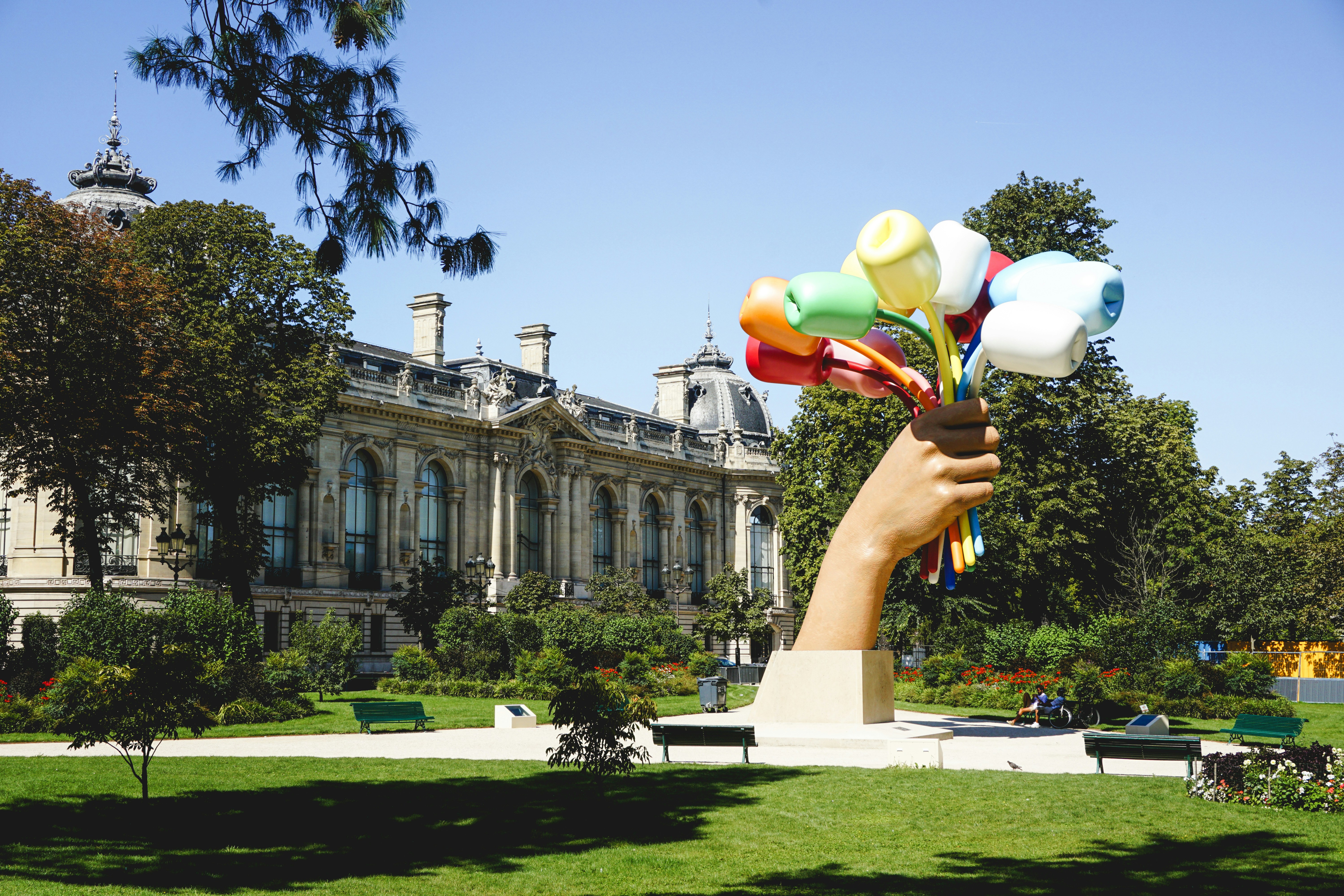 Giant hand sculpture holding colorful objects in park