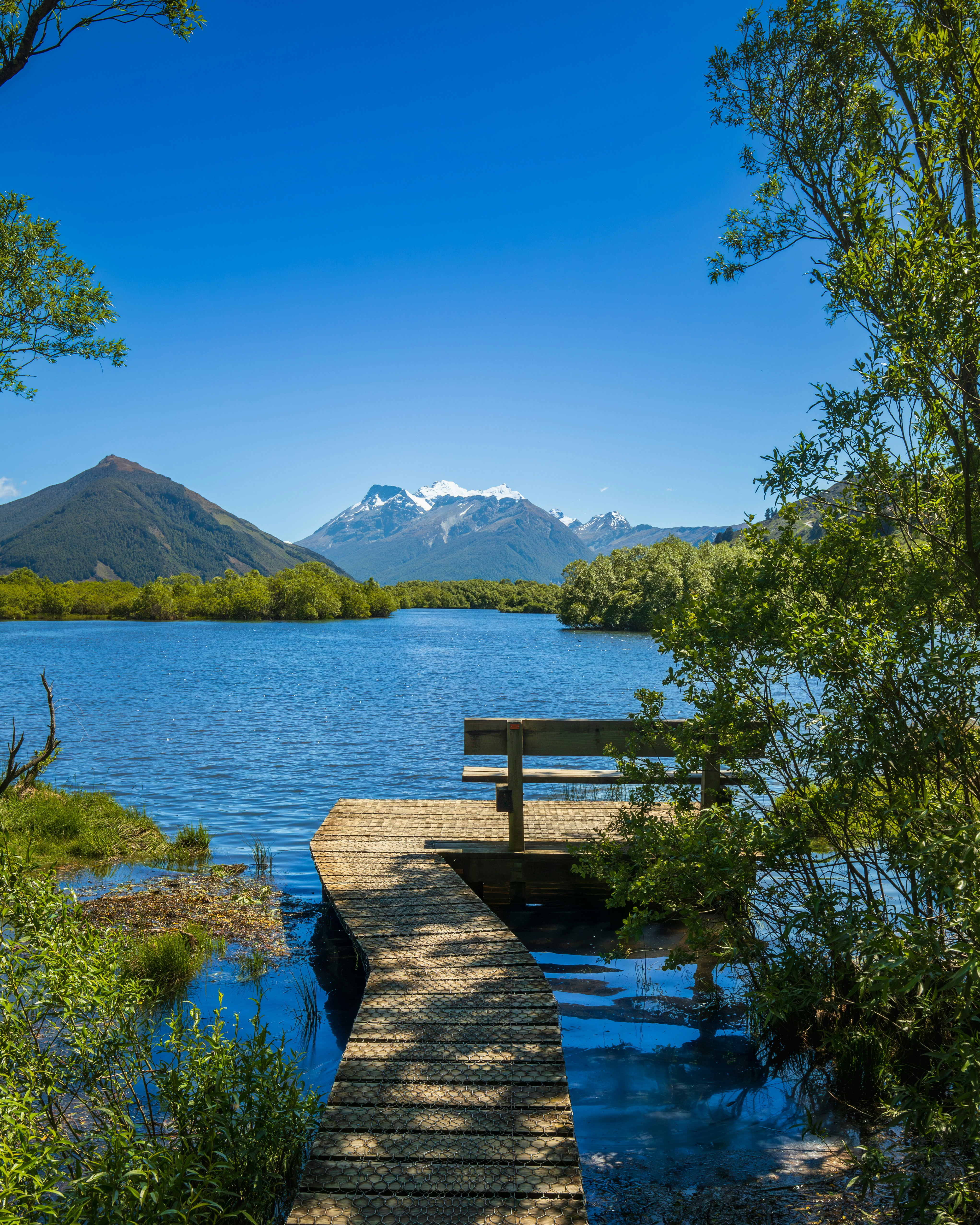 Wooden pier on a lake with mountains in background.