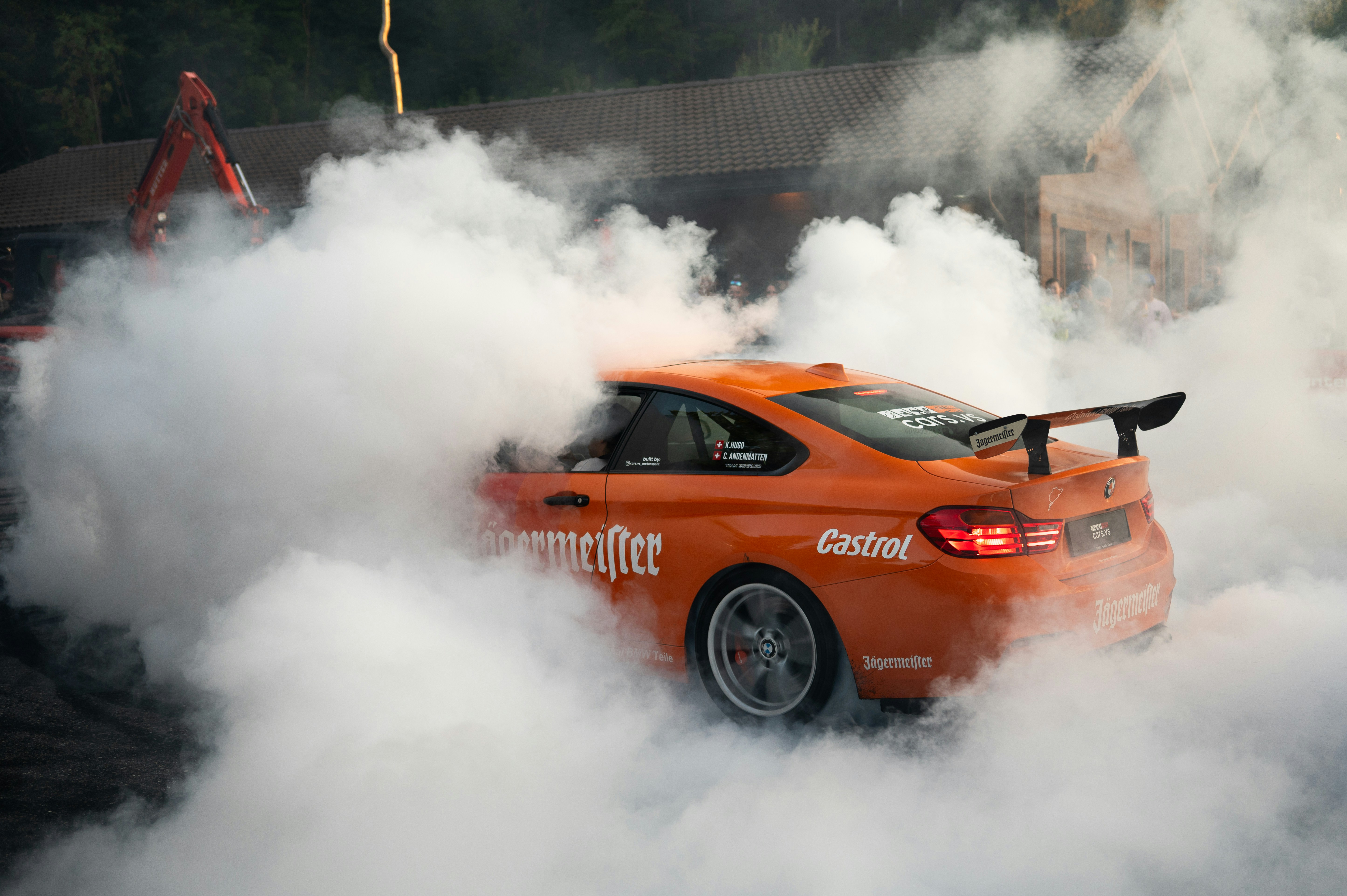 Orange car performing a drift surrounded by smoke
