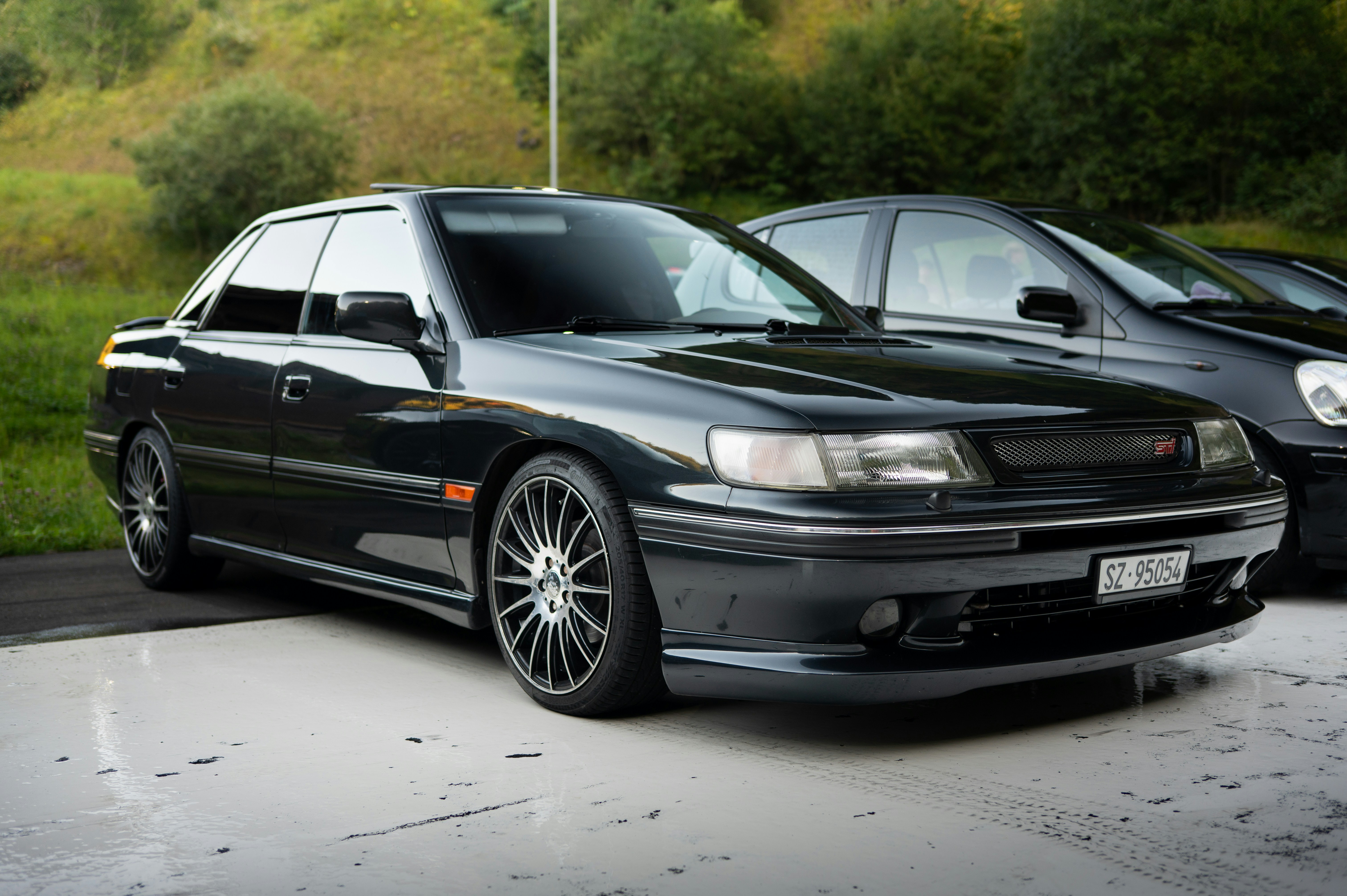 A sleek black sedan parked outdoors on a paved surface.
