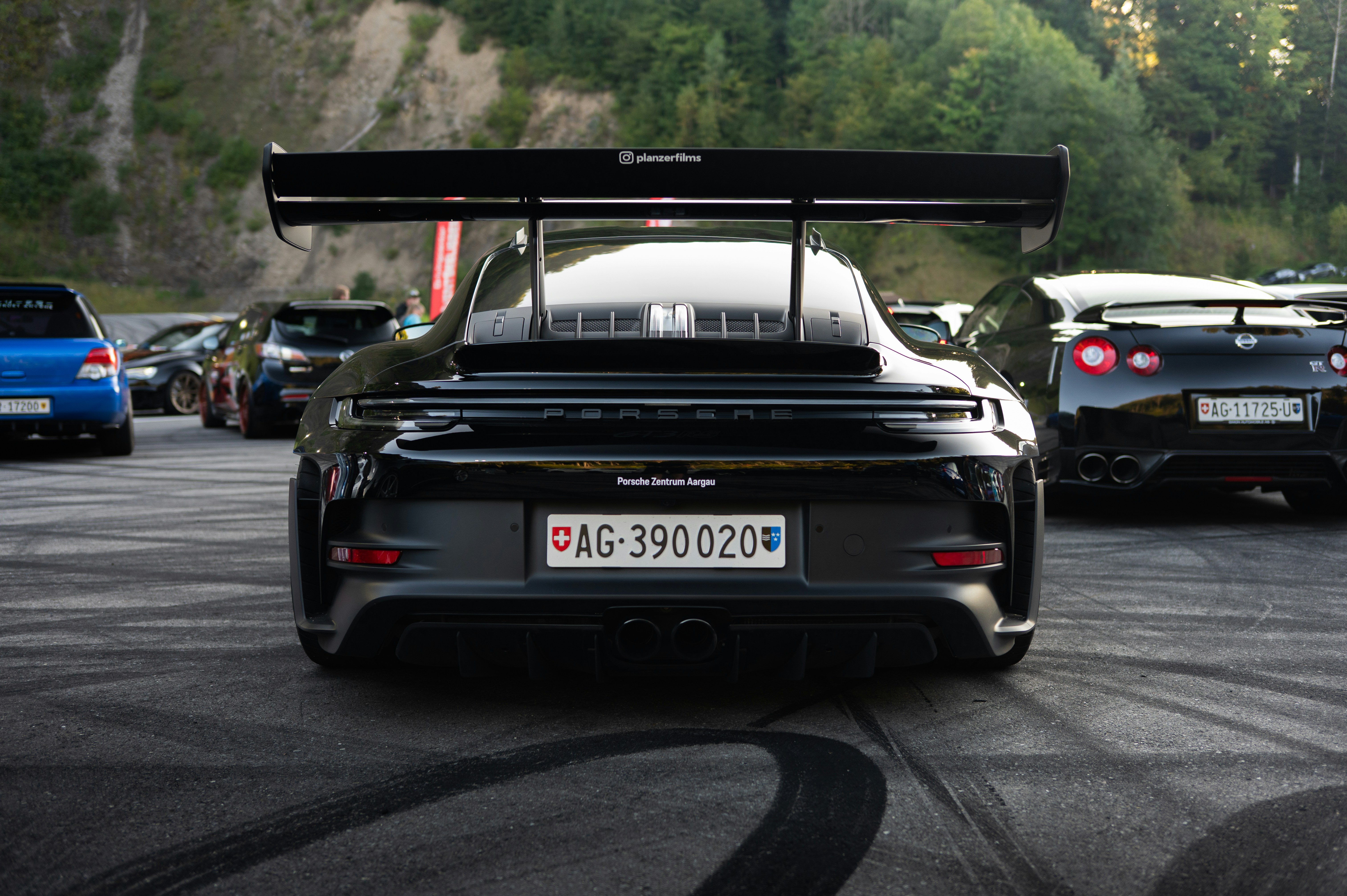 Black porsche gt3 with large rear spoiler parked on asphalt