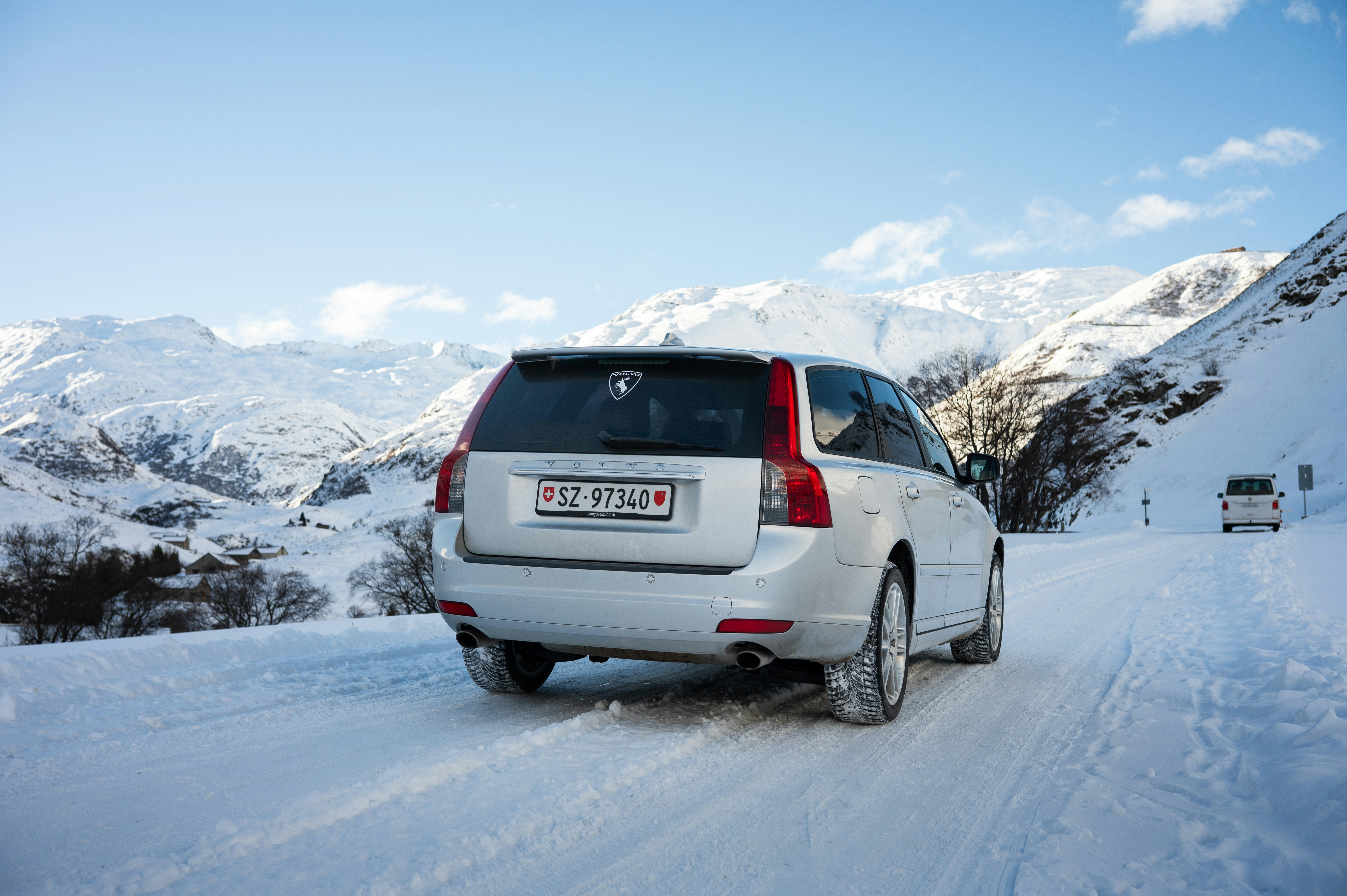 Silver car driving on a snowy mountain road.