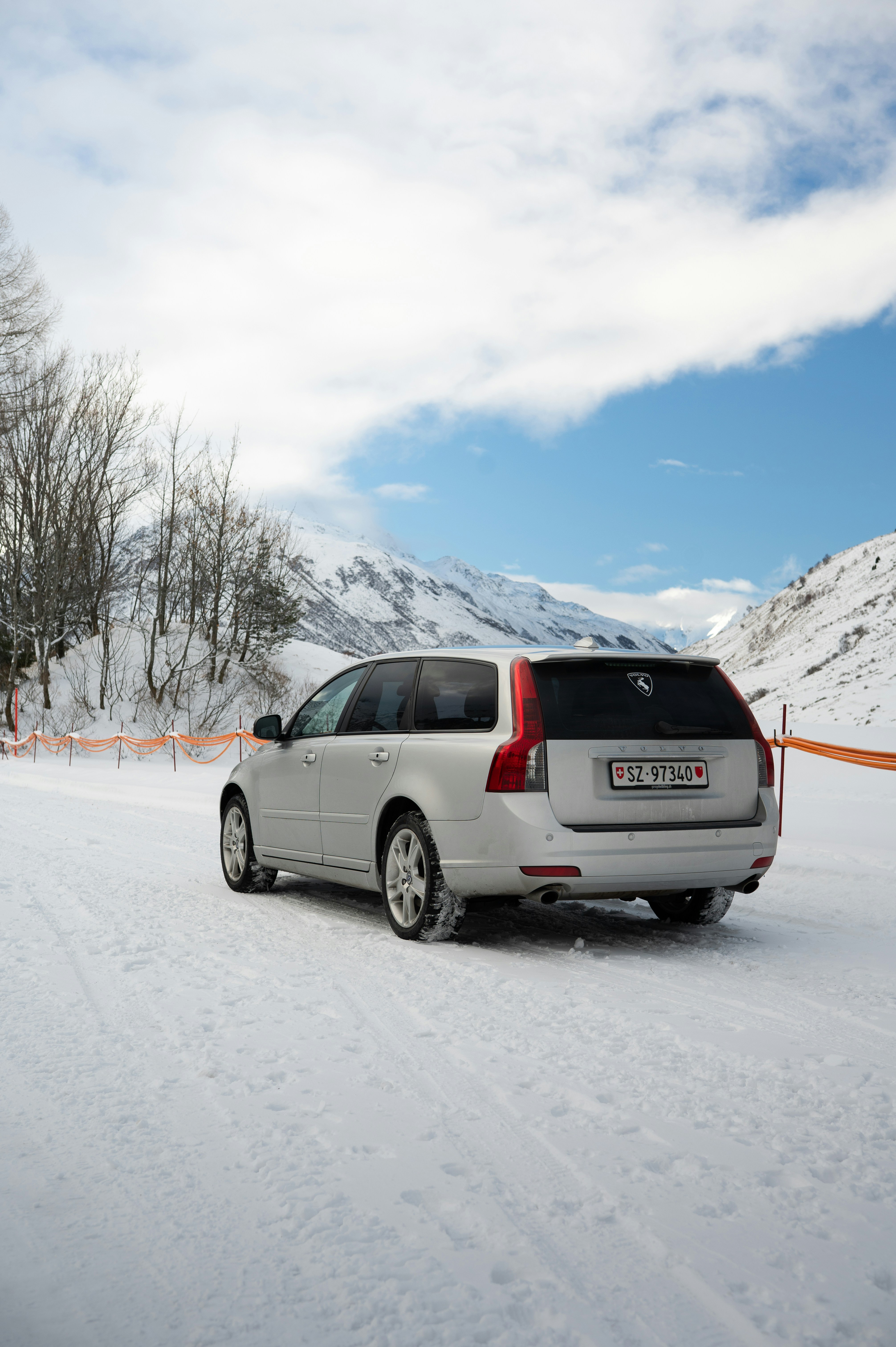 Silver station wagon parked on a snowy mountain road.