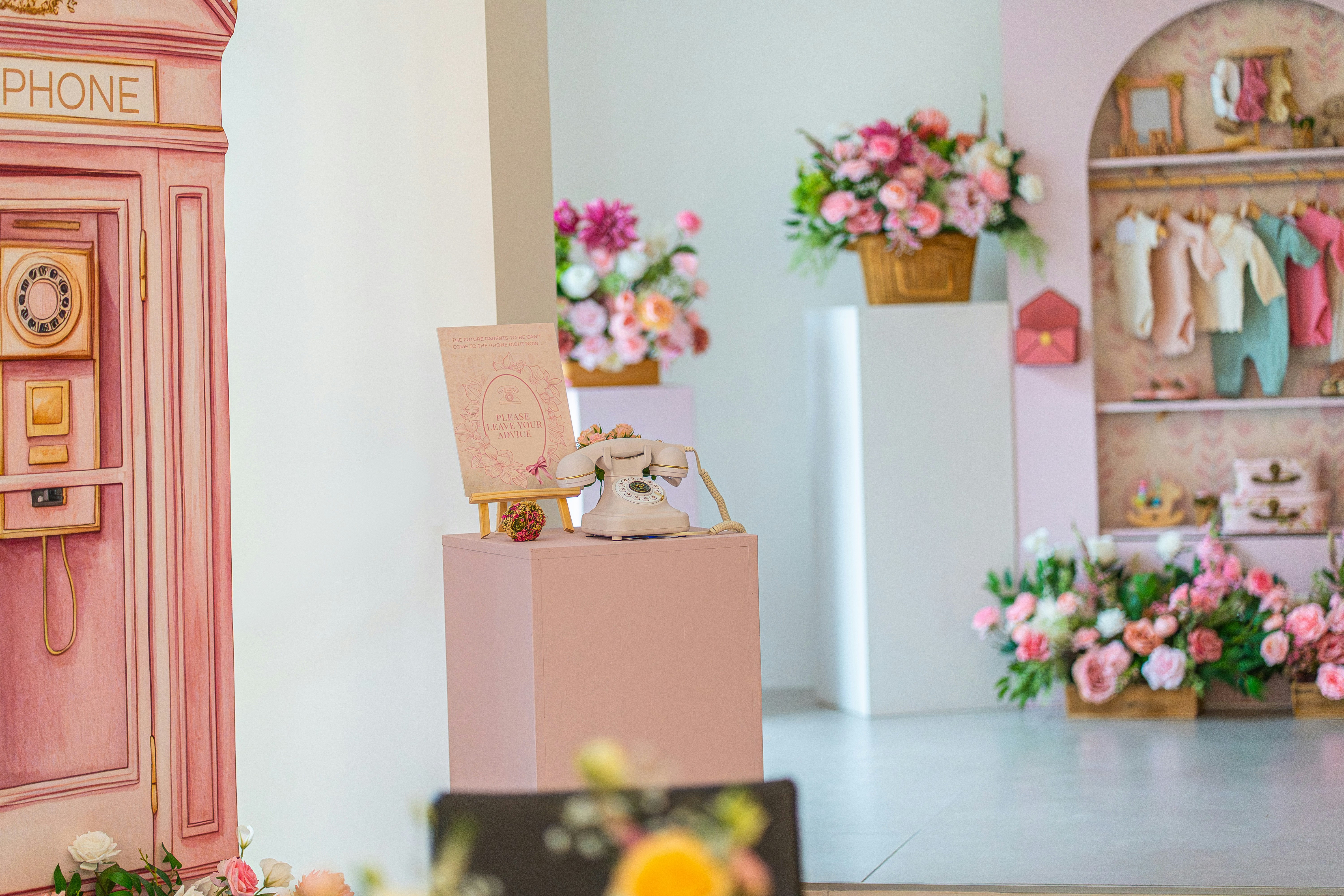 Pink telephone booth with flowers and baby clothes