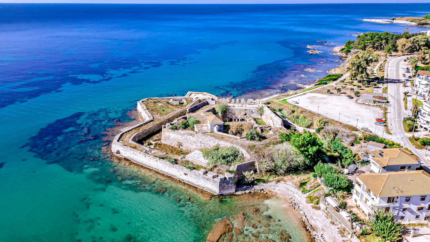 An old star-shaped fort on a low promontory seen from above, turquoise water on three sides