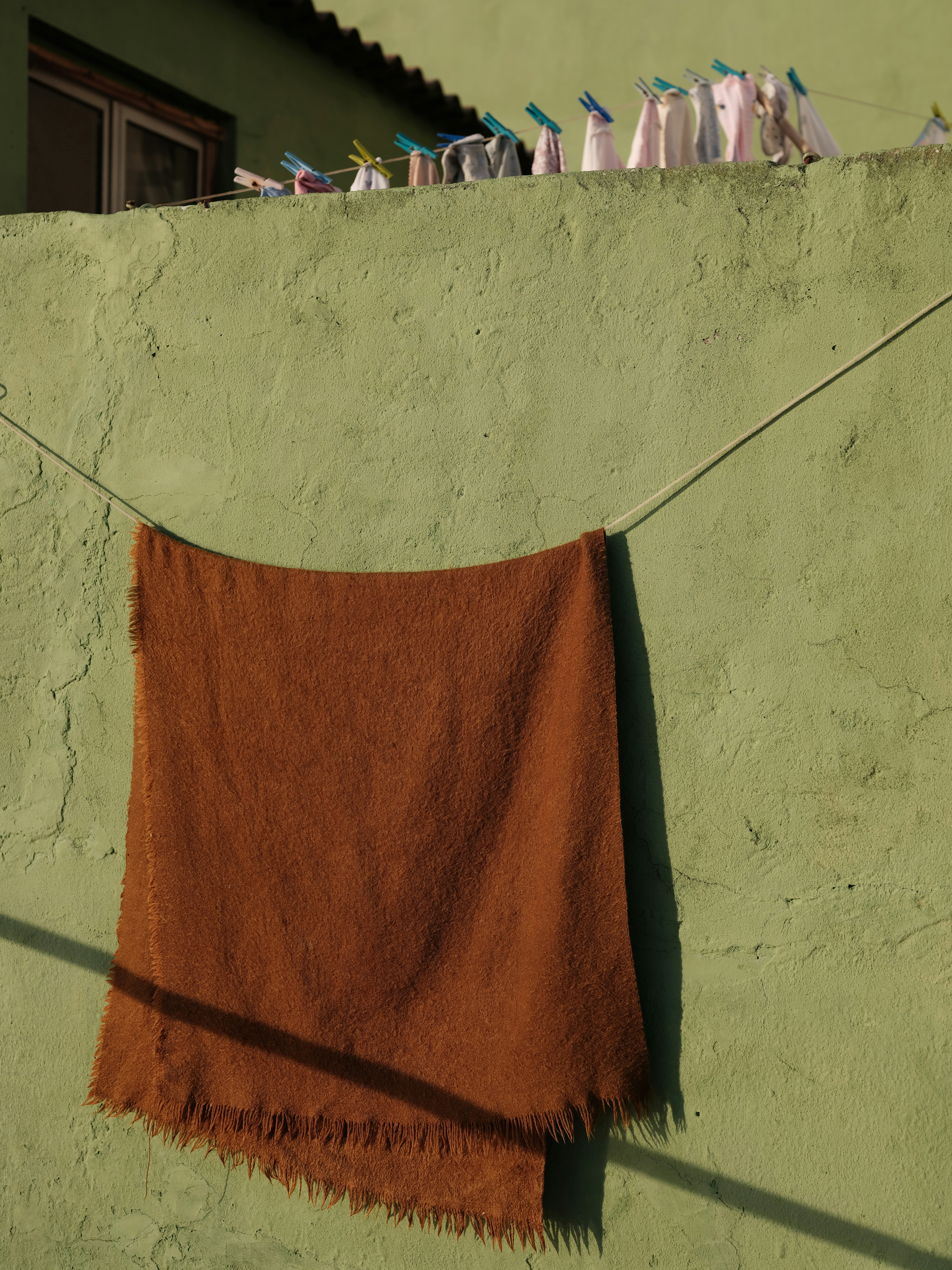 Brown blanket hanging on clothesline against green wall