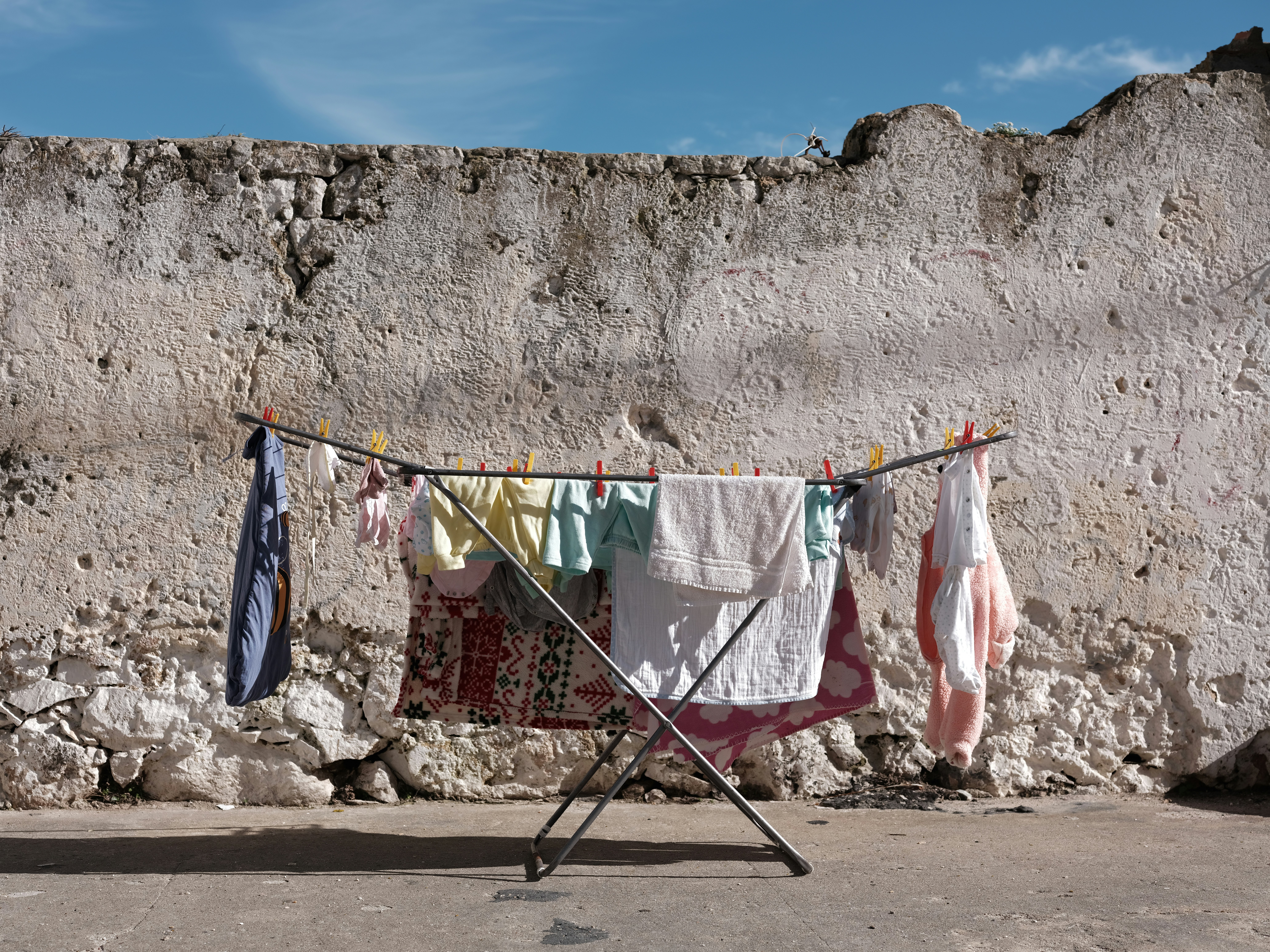 Clothes drying on a rack against a textured wall.