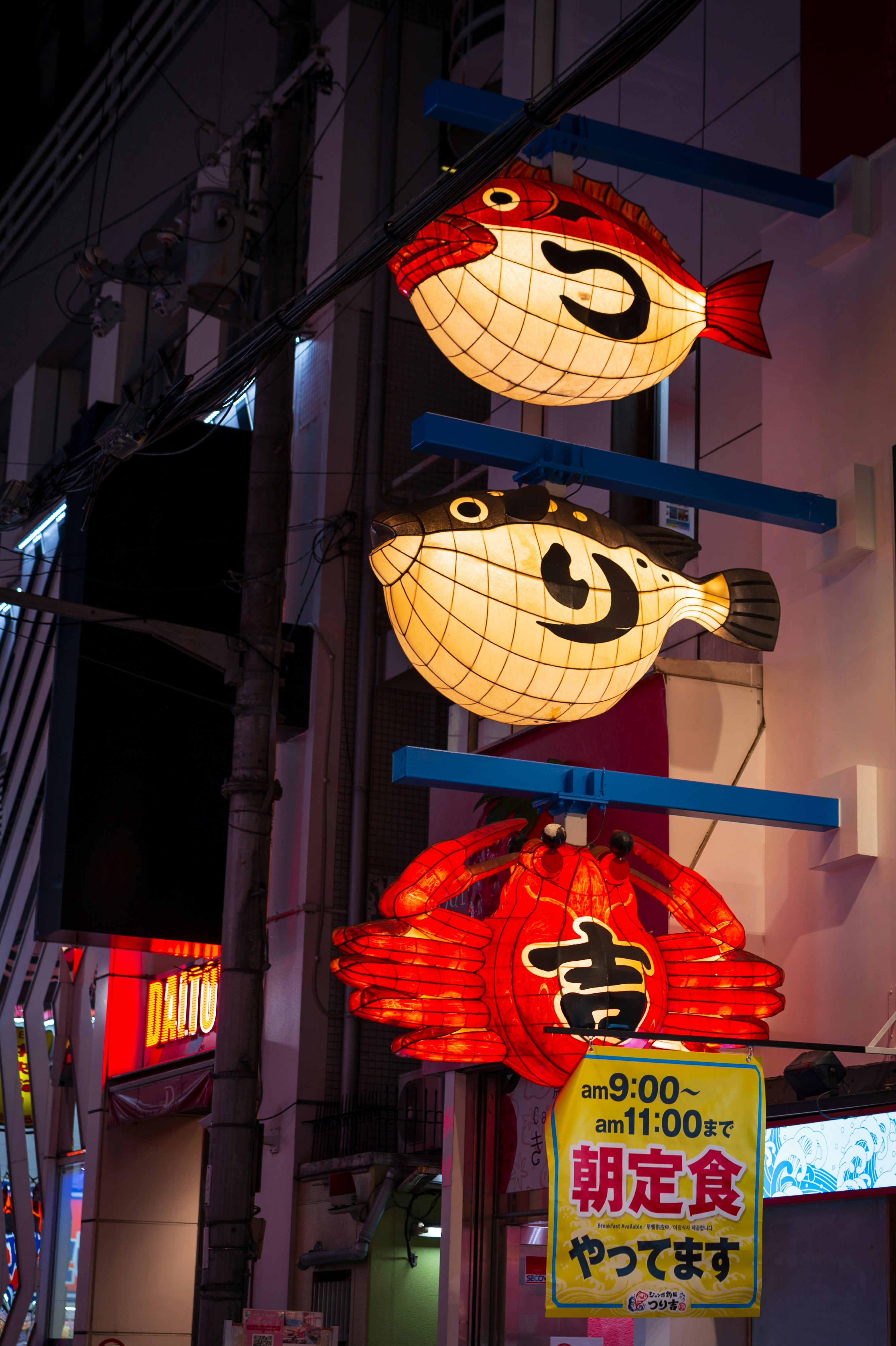 Three illuminated lanterns shaped like fish and a crab.