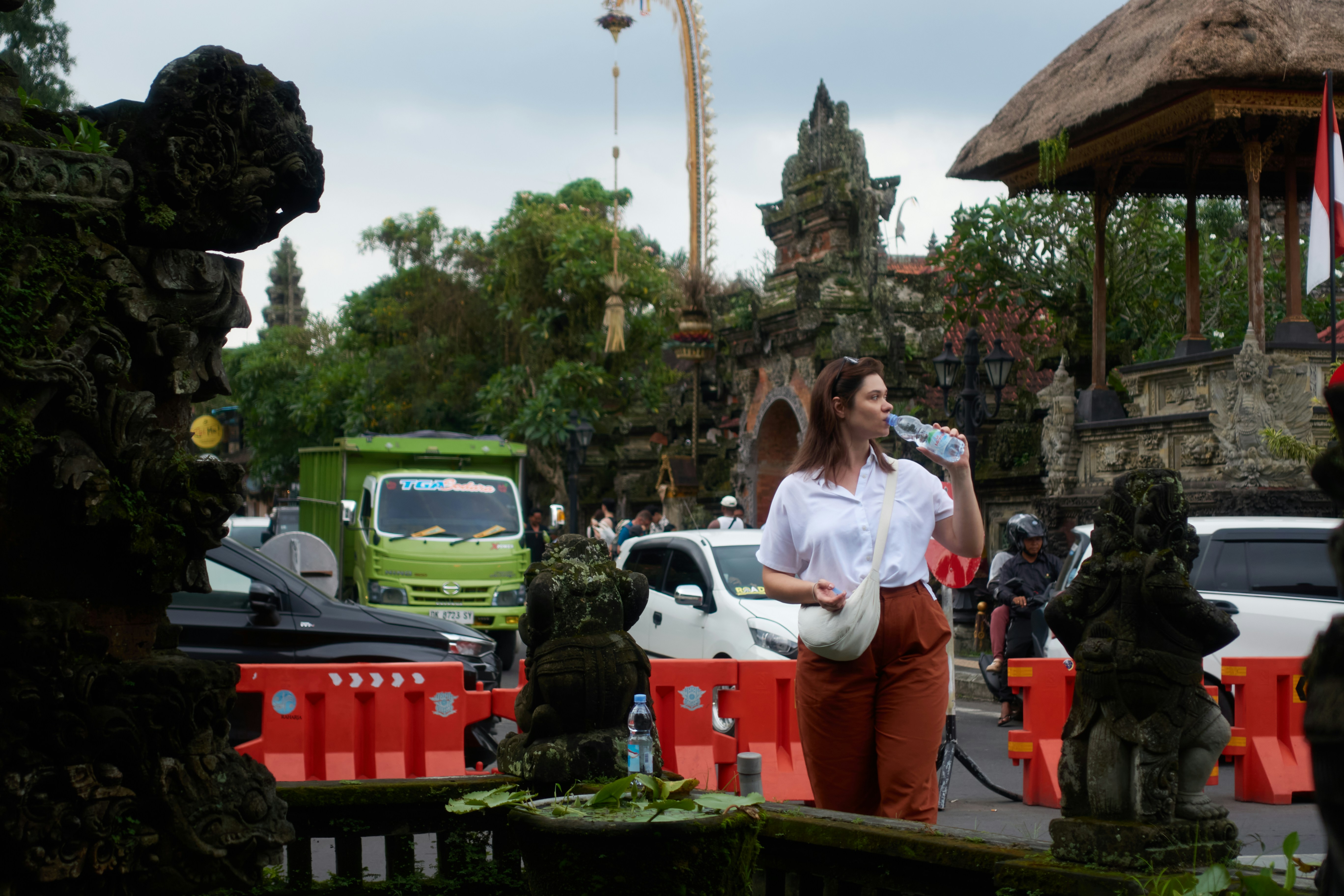 A traveller drinking water beside ornate stone carvings — the kind of sacred space where shoulder, knee, and shoe etiquette becomes non-negotiable