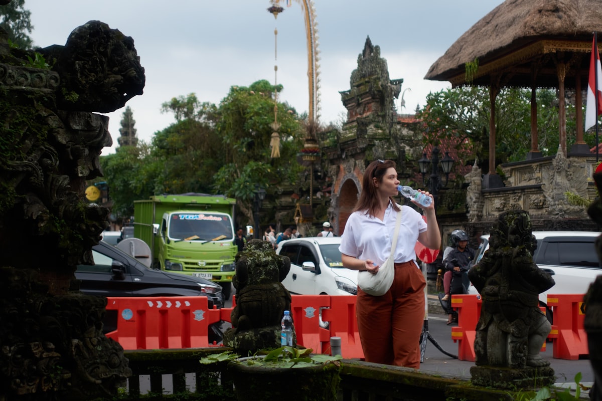 Woman drinking water near ornate stone carvings