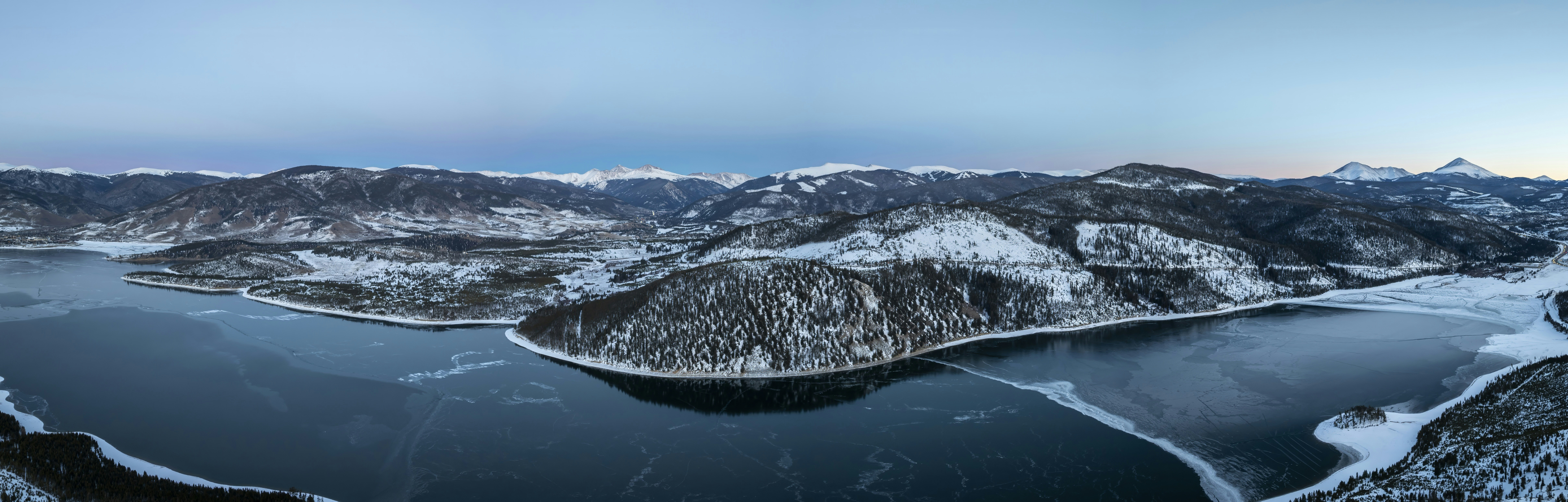 Snow-covered mountains and frozen lake under clear sky