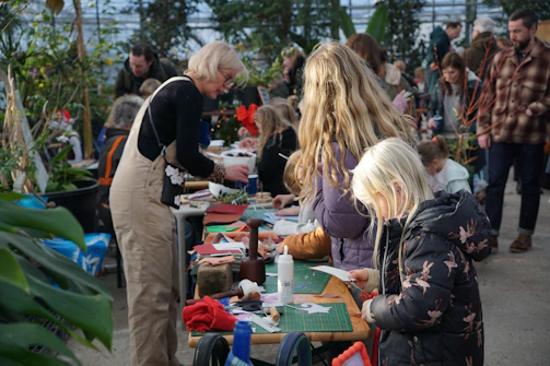 Adults and children crafting at tables with plants