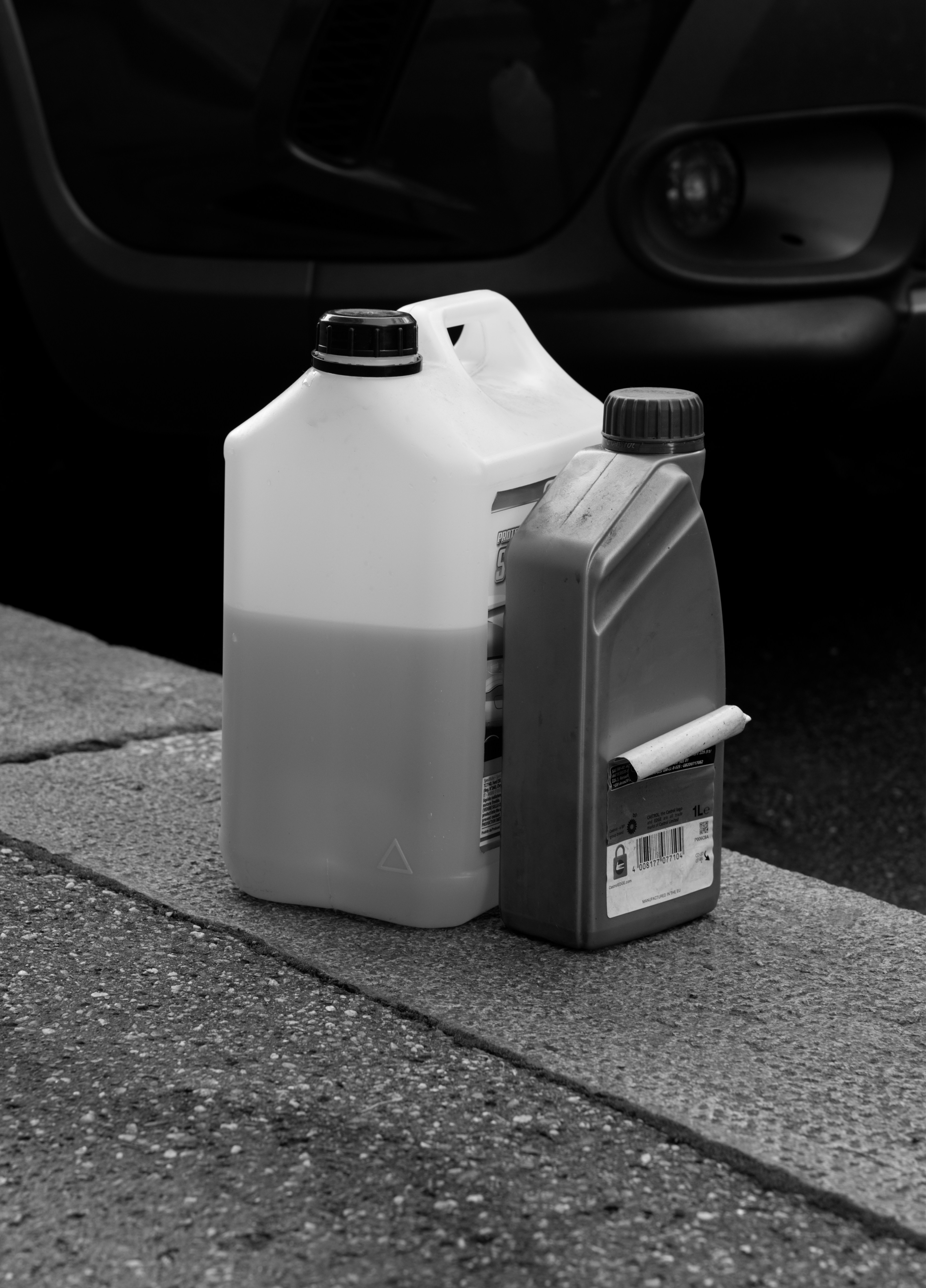Two plastic containers of liquid on a curb.