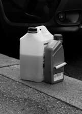 Two plastic containers of oil change liquid on a curb