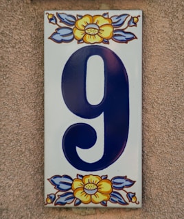 A decorative ceramic house number nine