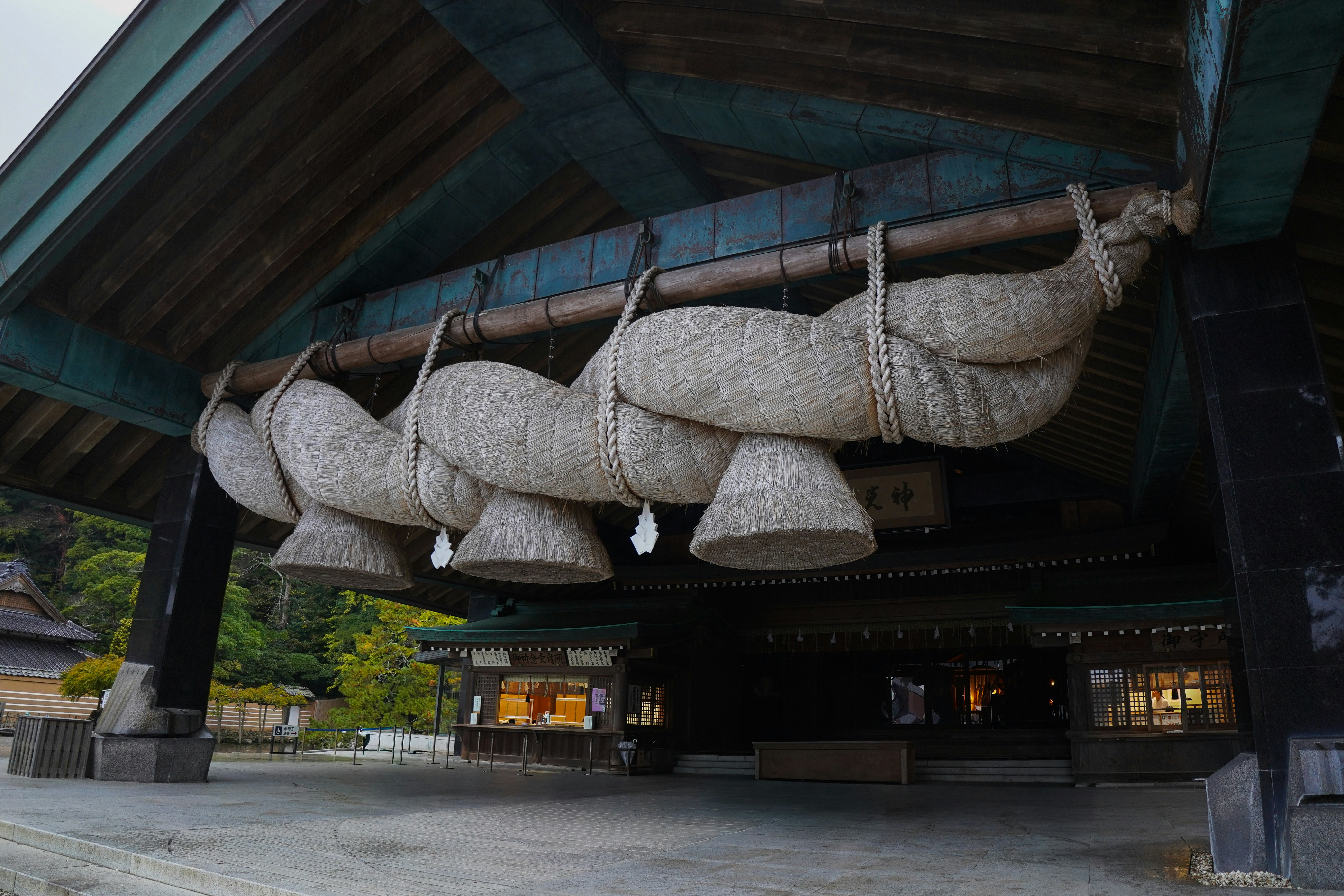 Large straw ropes hang from a traditional japanese shrine building.