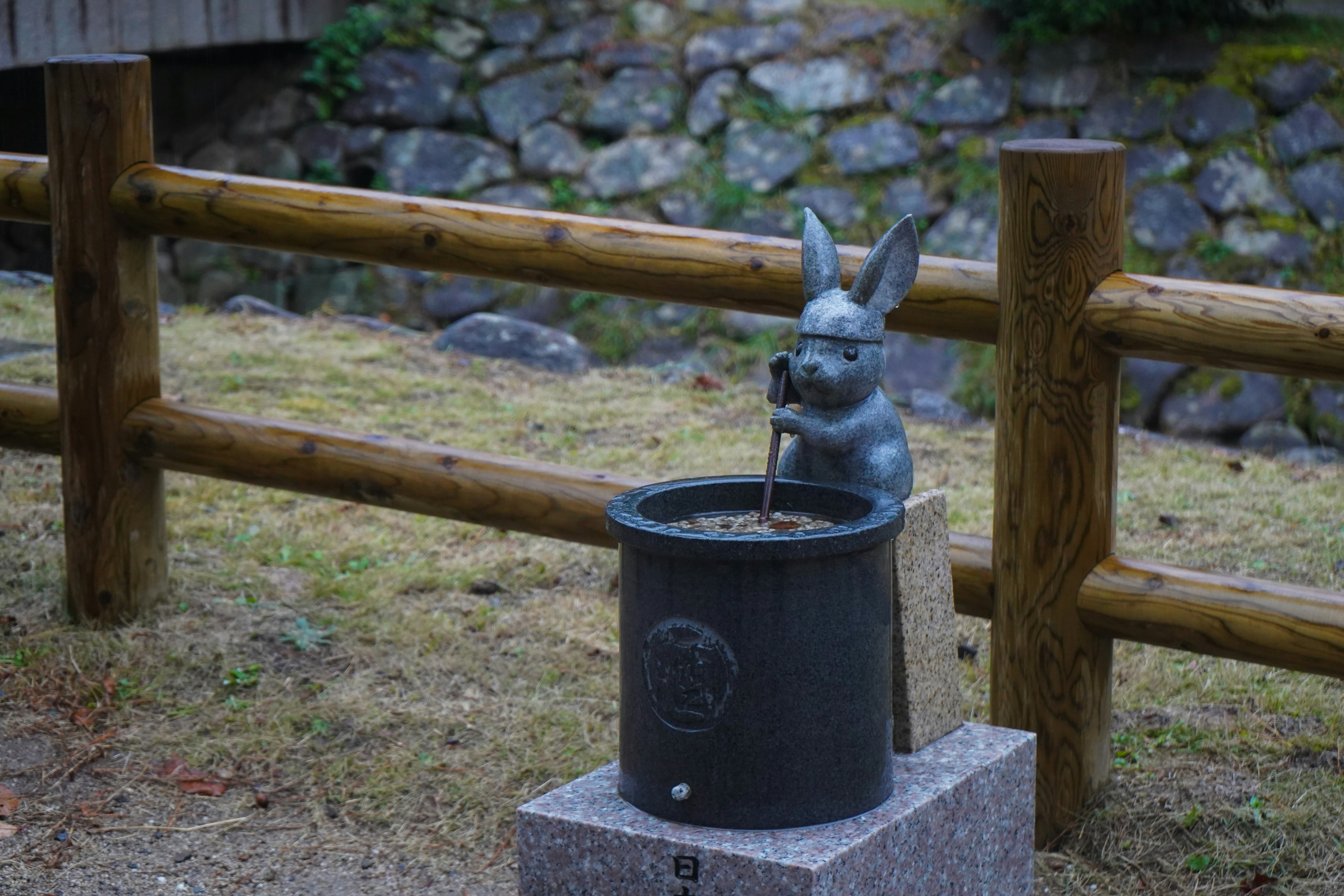 Bronze rabbit statue by a wooden fence
