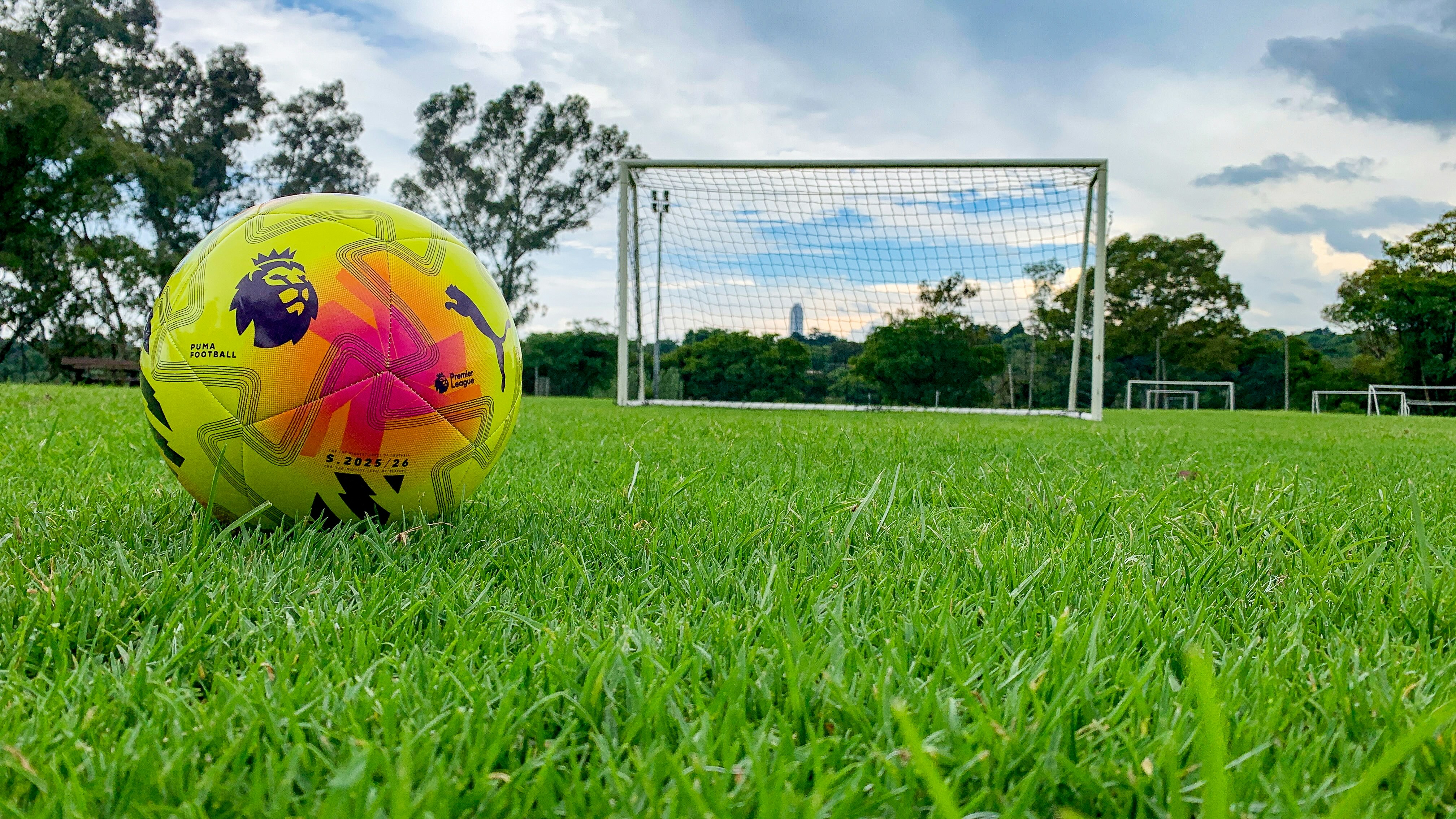 Balón de fútbol sobre césped verde cerca de una portería.