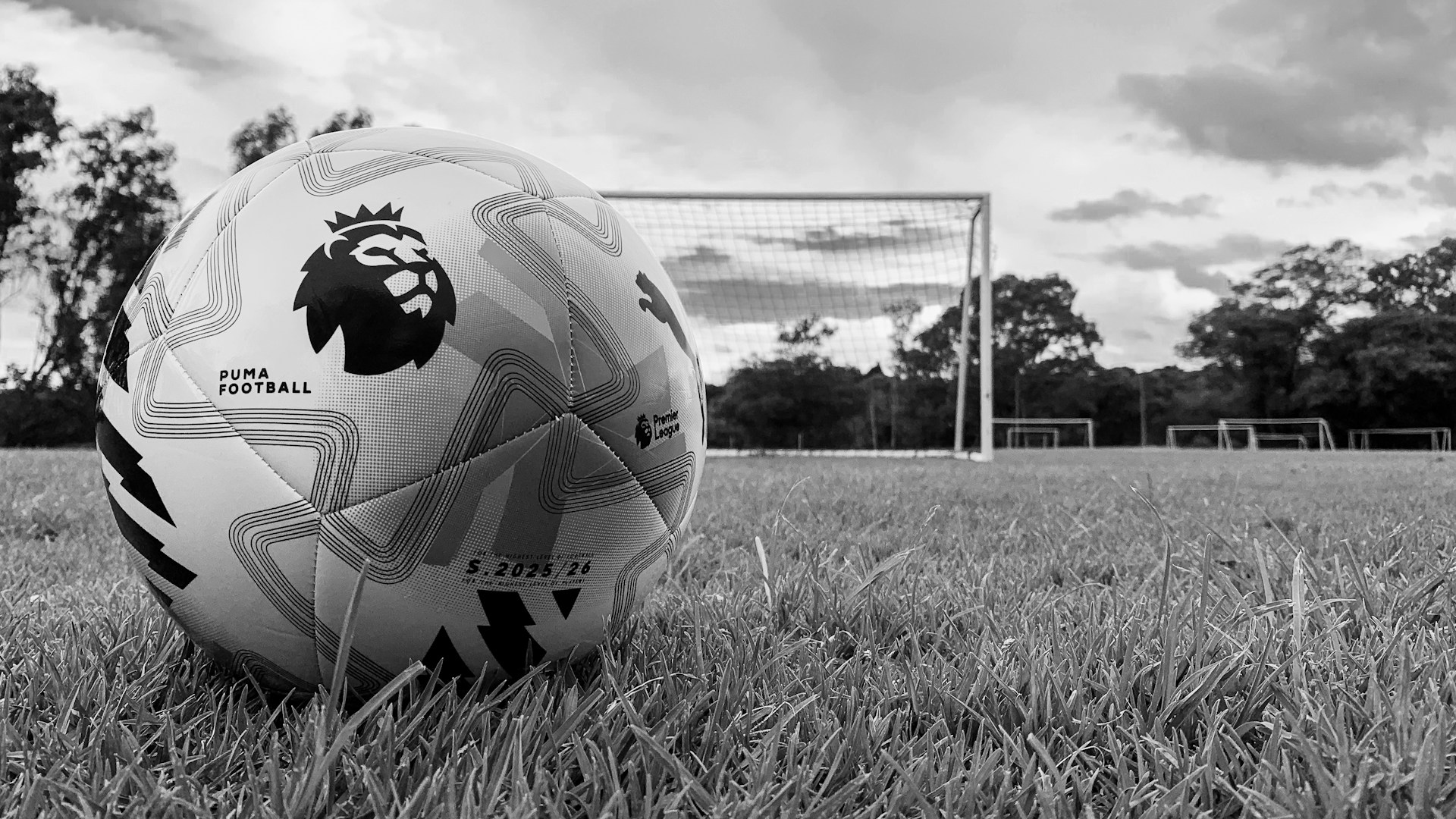 A soccer ball on a grassy field with goalposts.