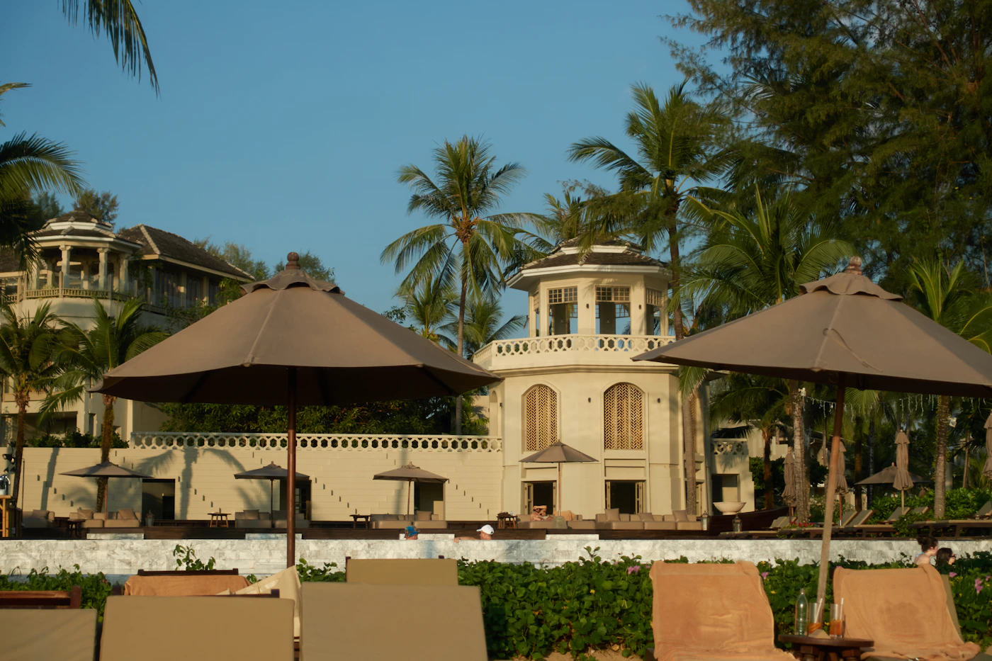Palm Beach resort architecture with pool, palm trees, and beach umbrellas