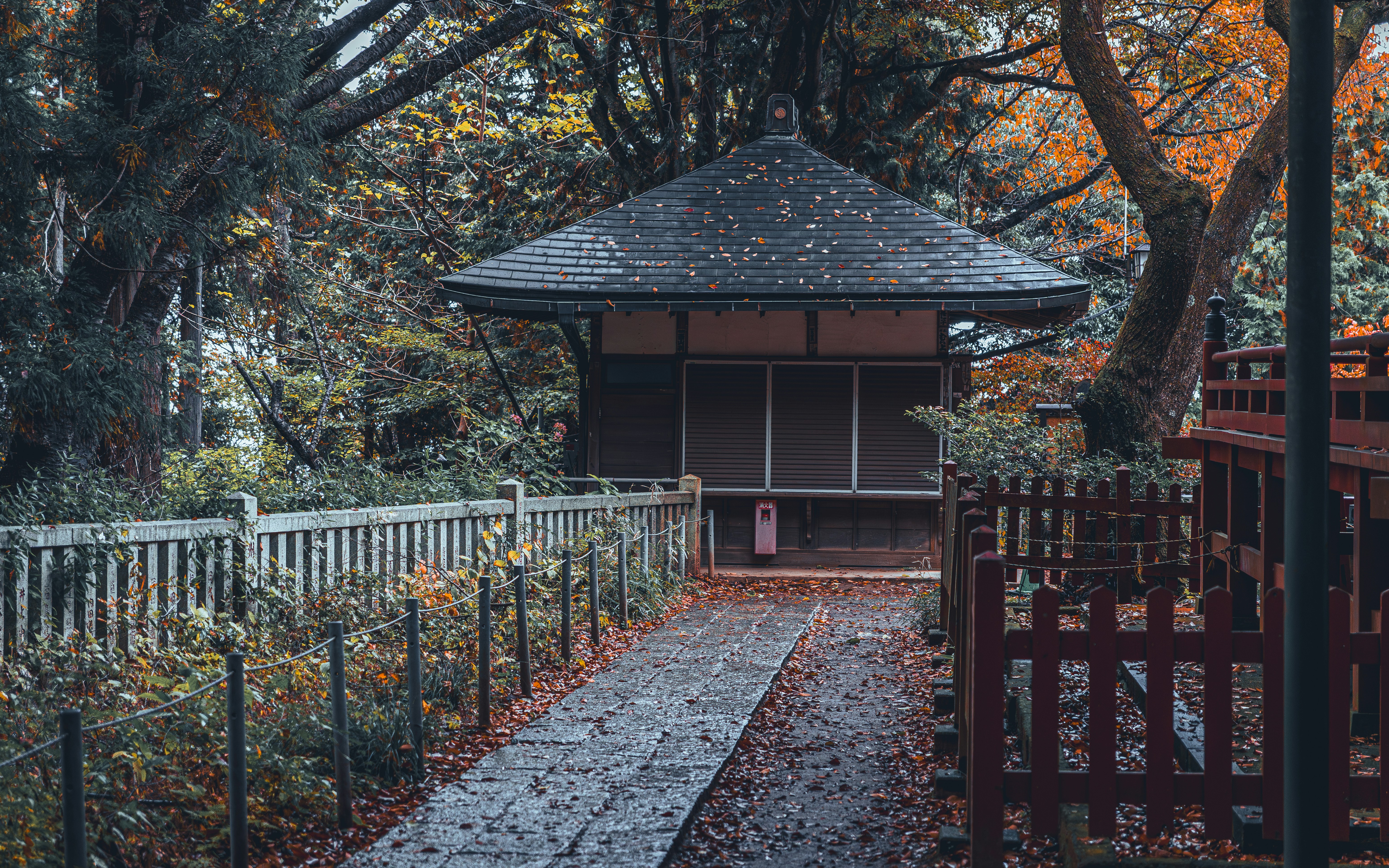 A small traditional japanese building in a park.