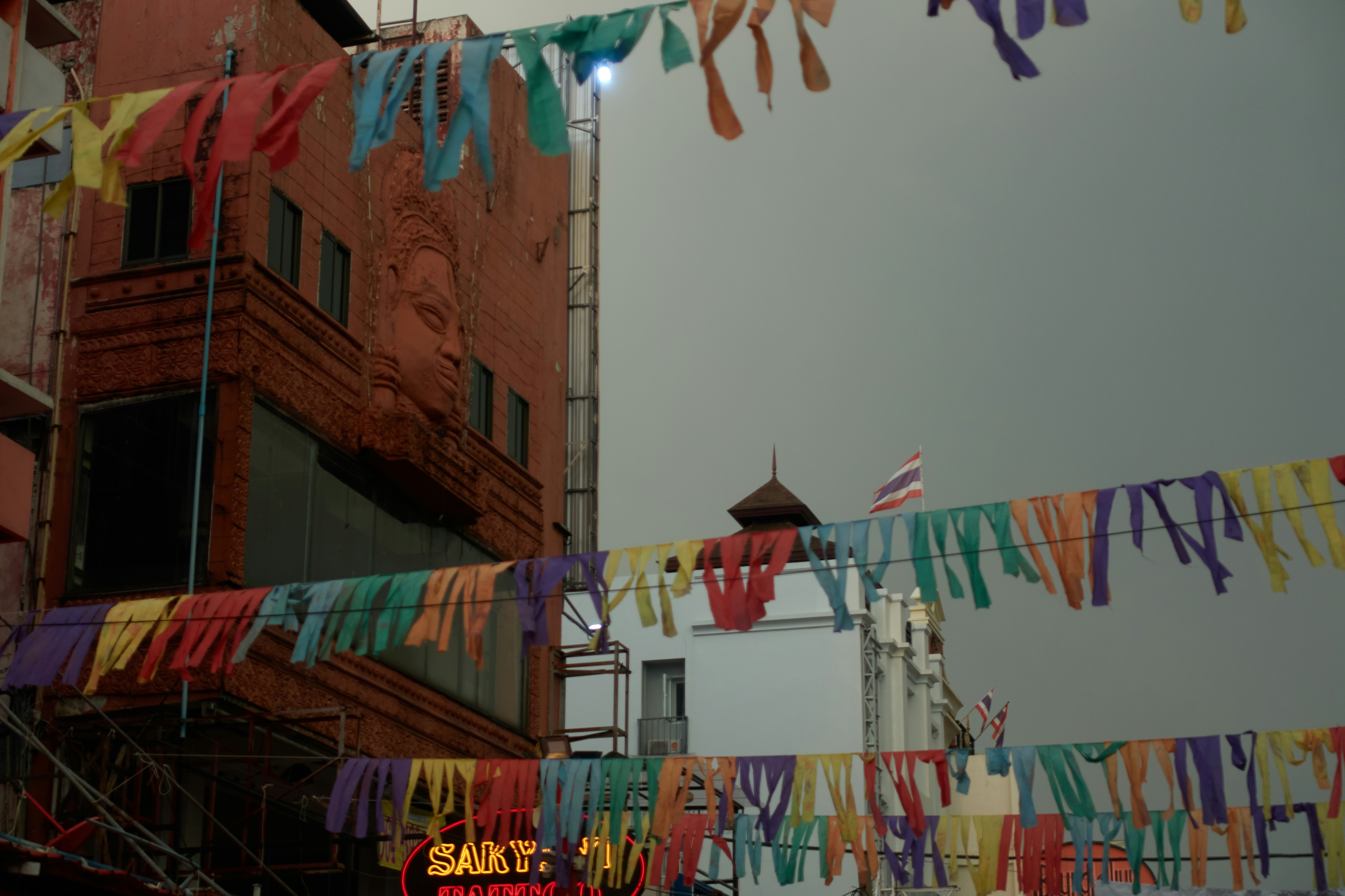 Bandeiras festivas coloridas pendem entre os prédios.