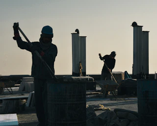 Construction workers silhouetted against the sky