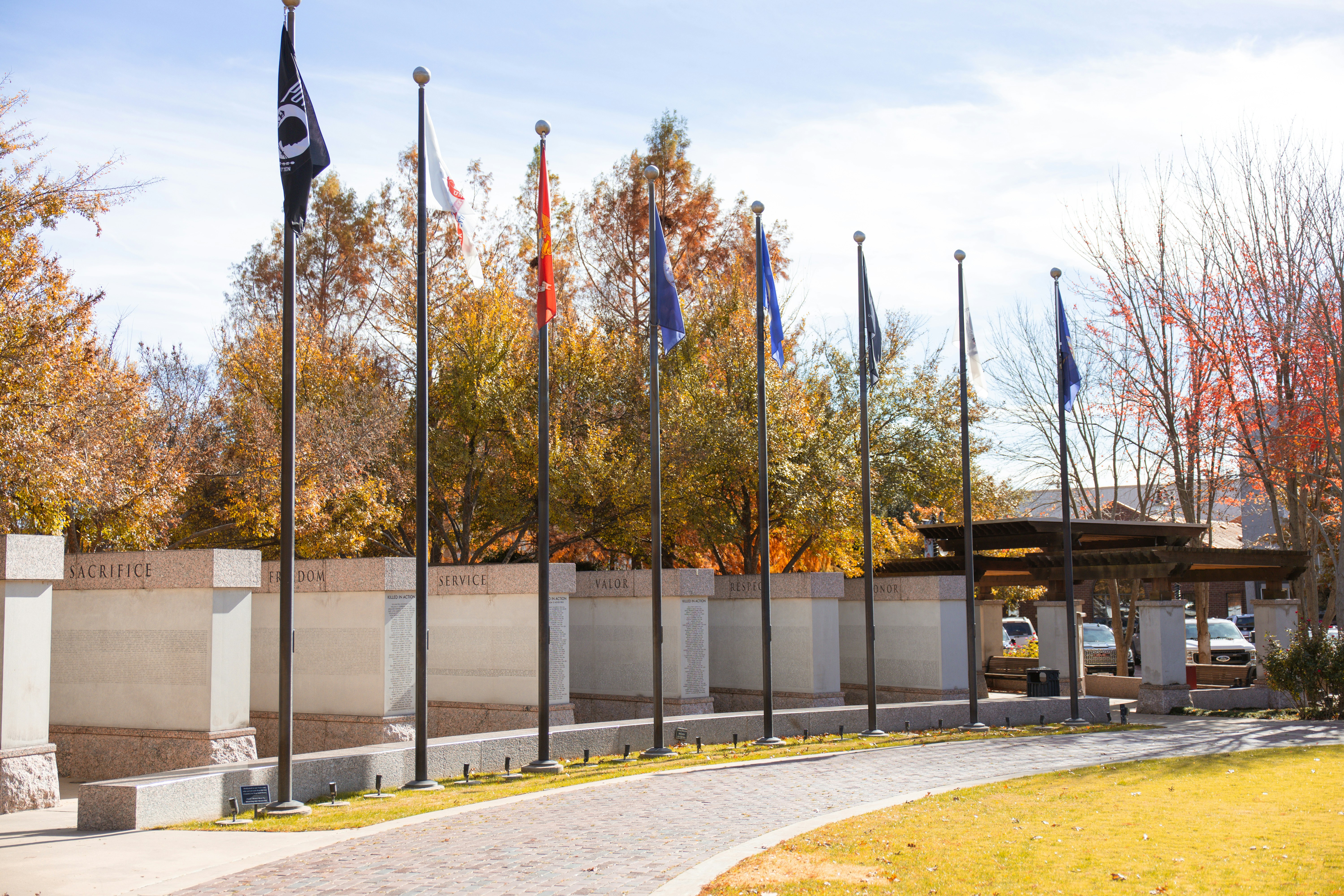 Row of flags with autumn trees and walkway