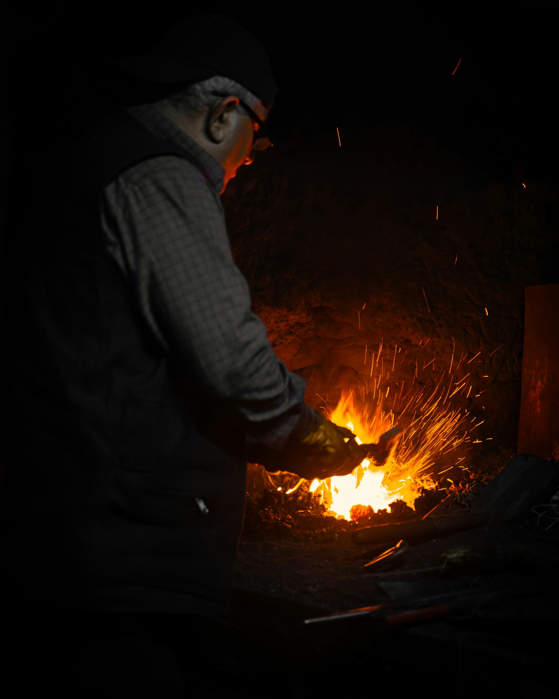 Blacksmith working at a glowing forge with sparks