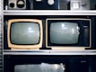 Two vintage televisions on a shelf