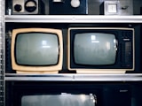 Two vintage televisions on a shelf