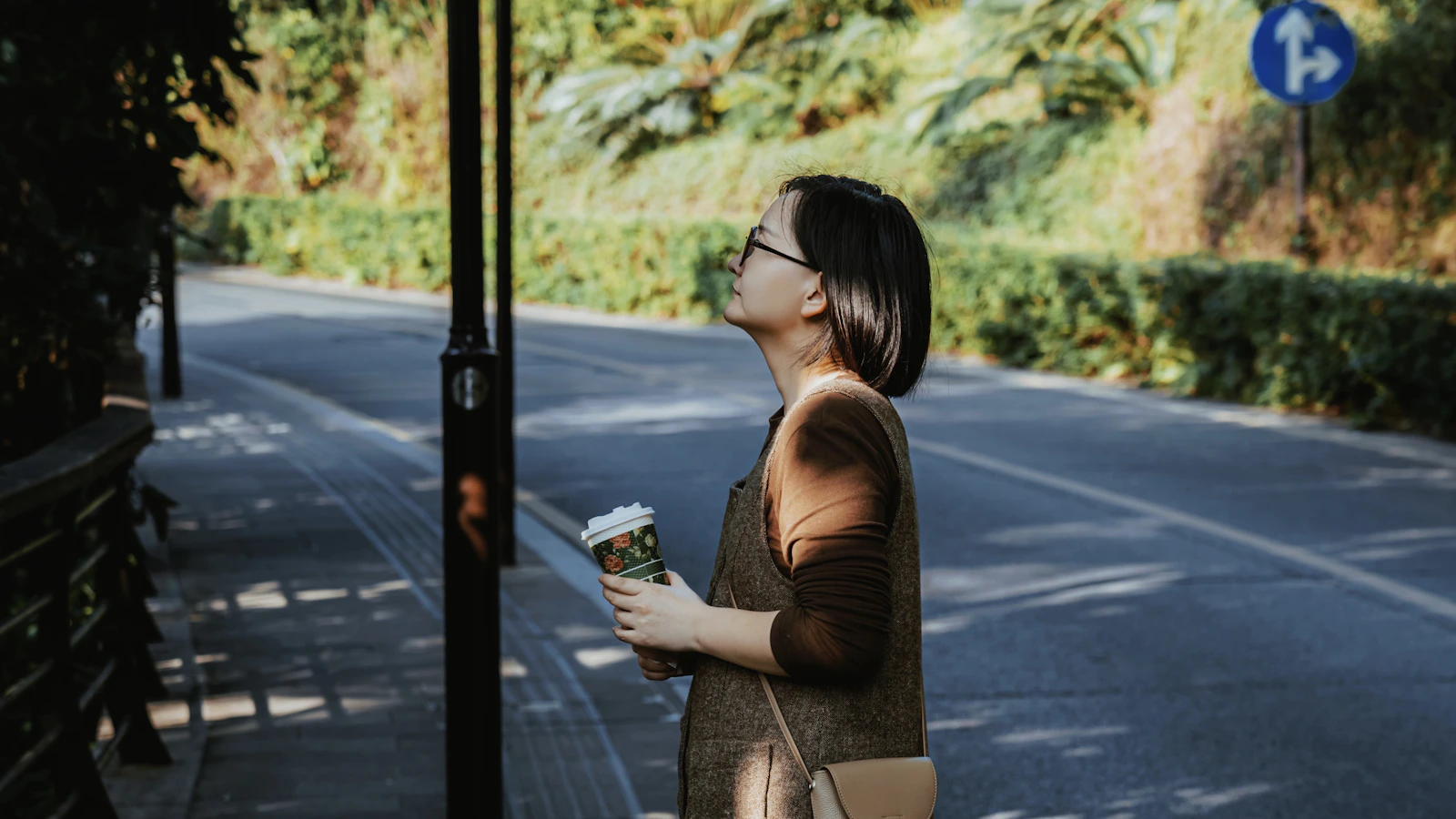 A woman holding a coffee cup, looking up in thought