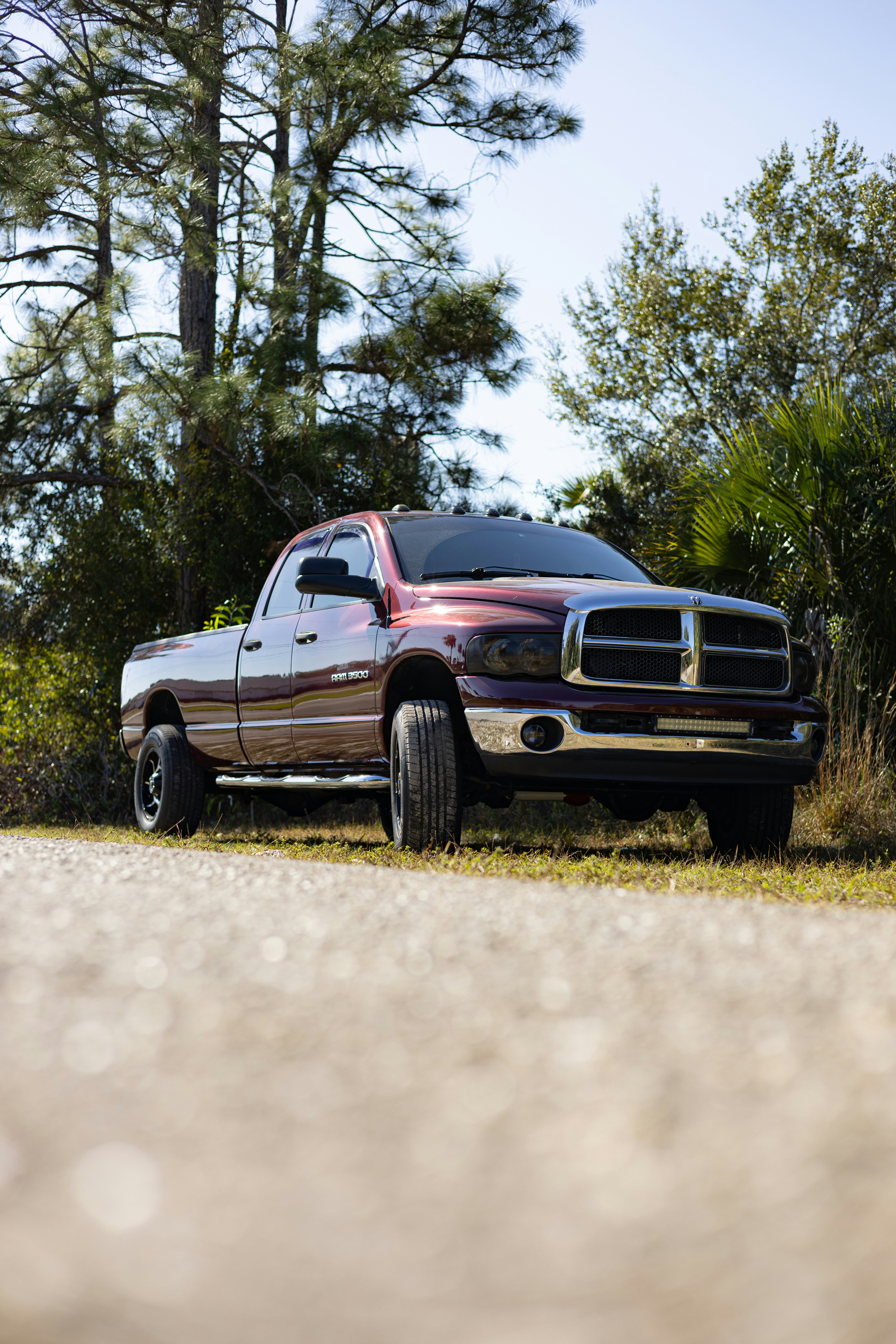 Maroon pickup truck parked on a gravel road.
