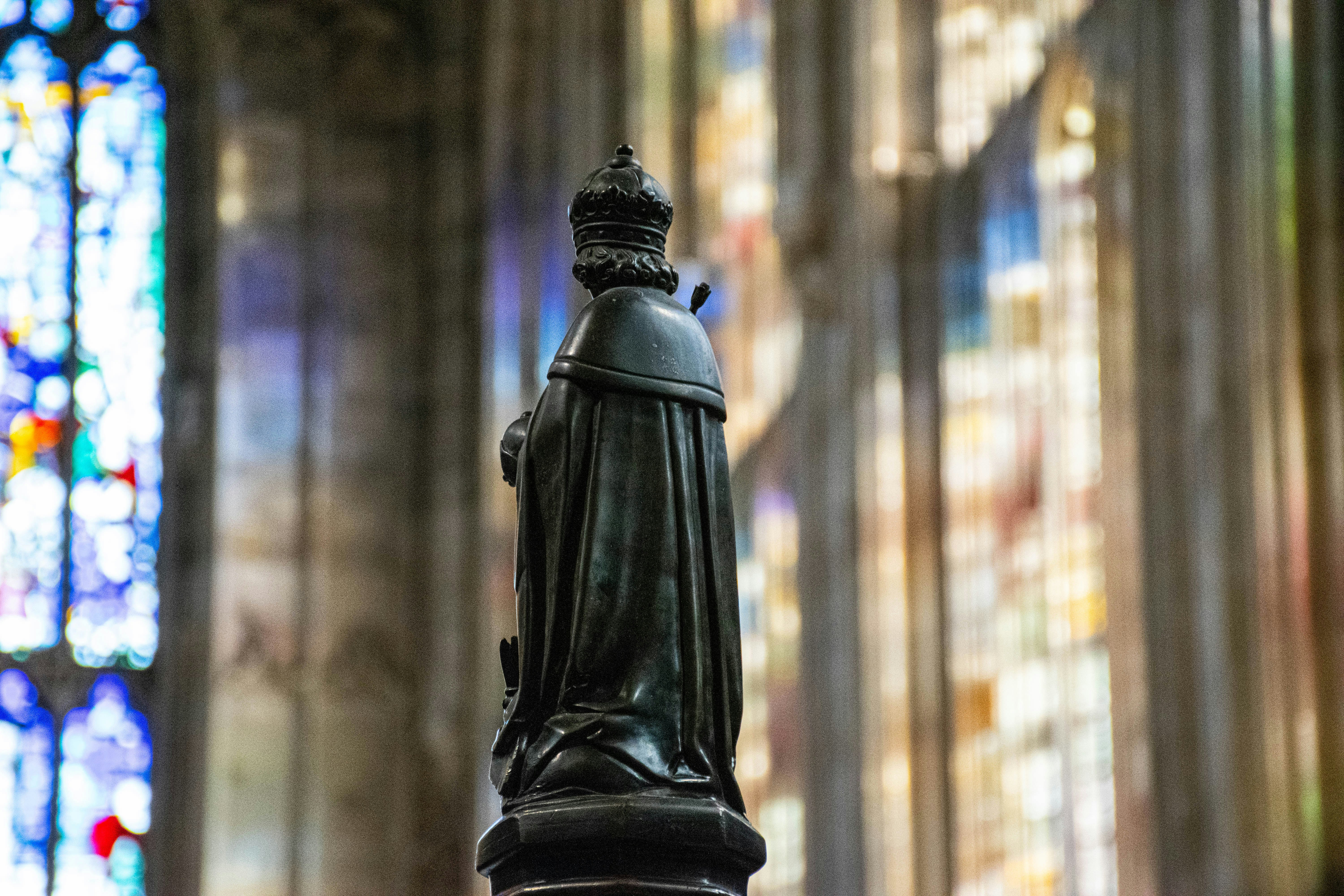 Estatua de un rey en una catedral con vidrieras.