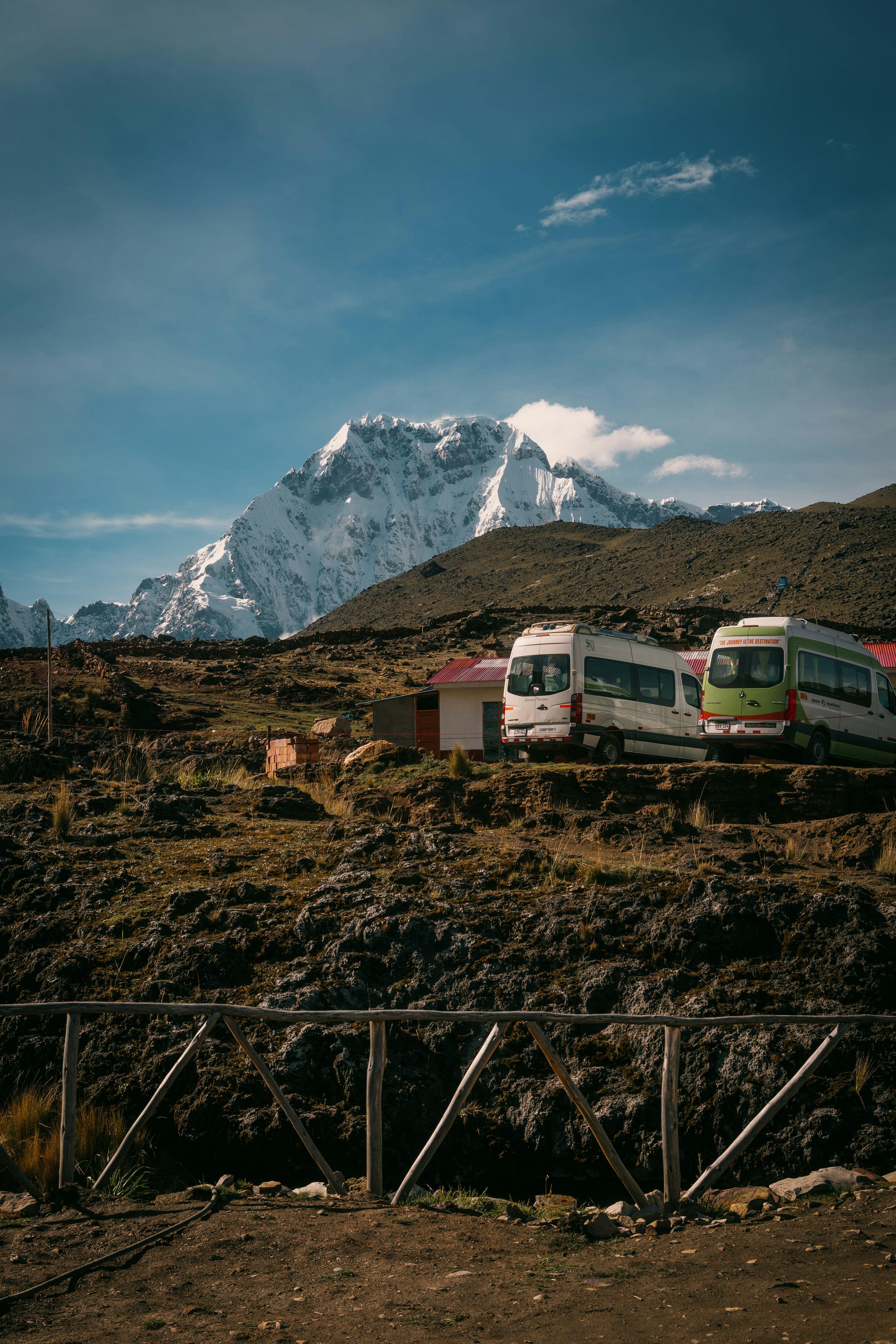 Deux bus garés sur fond de montagne enneigée.