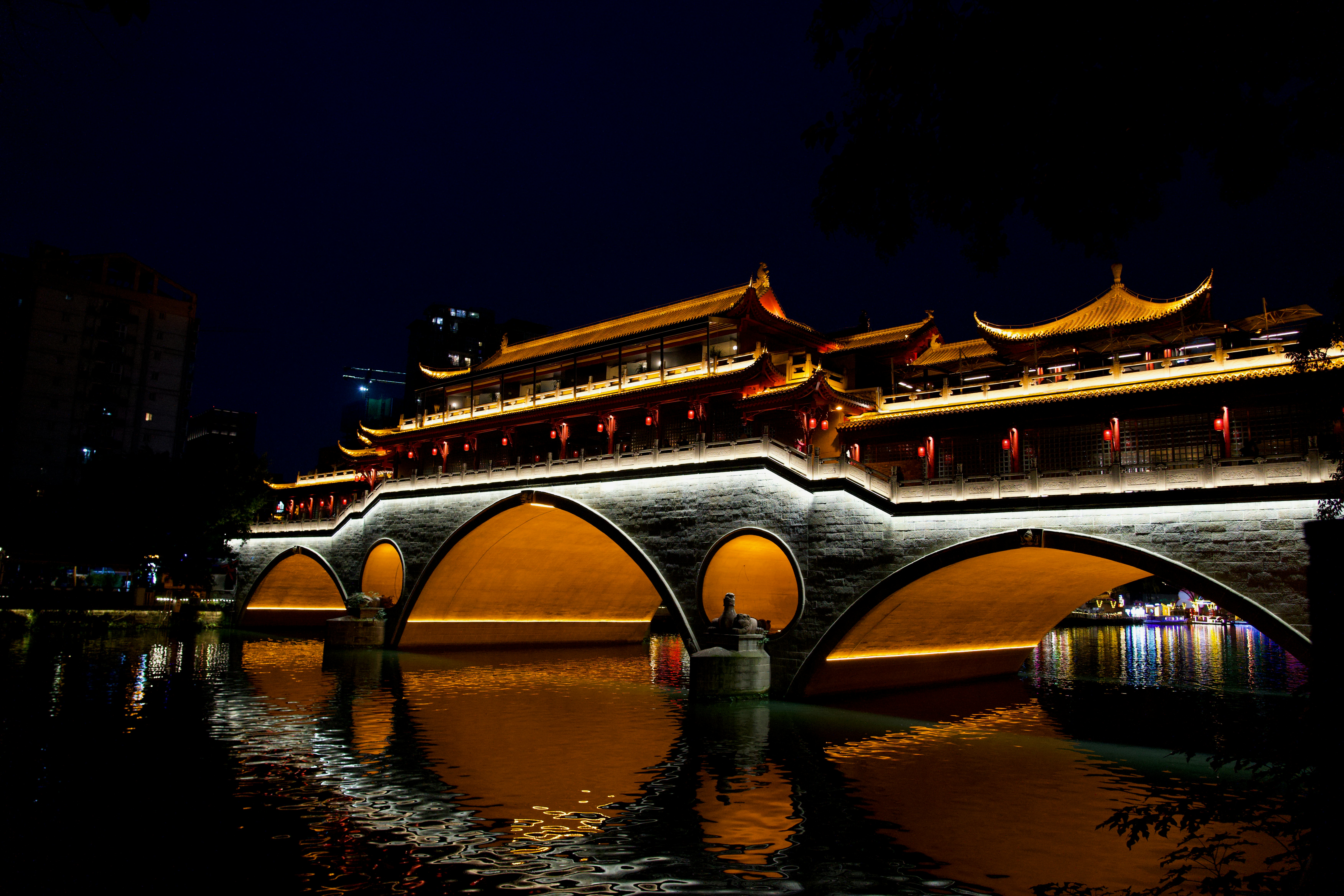 Illuminated traditional chinese bridge over water at night