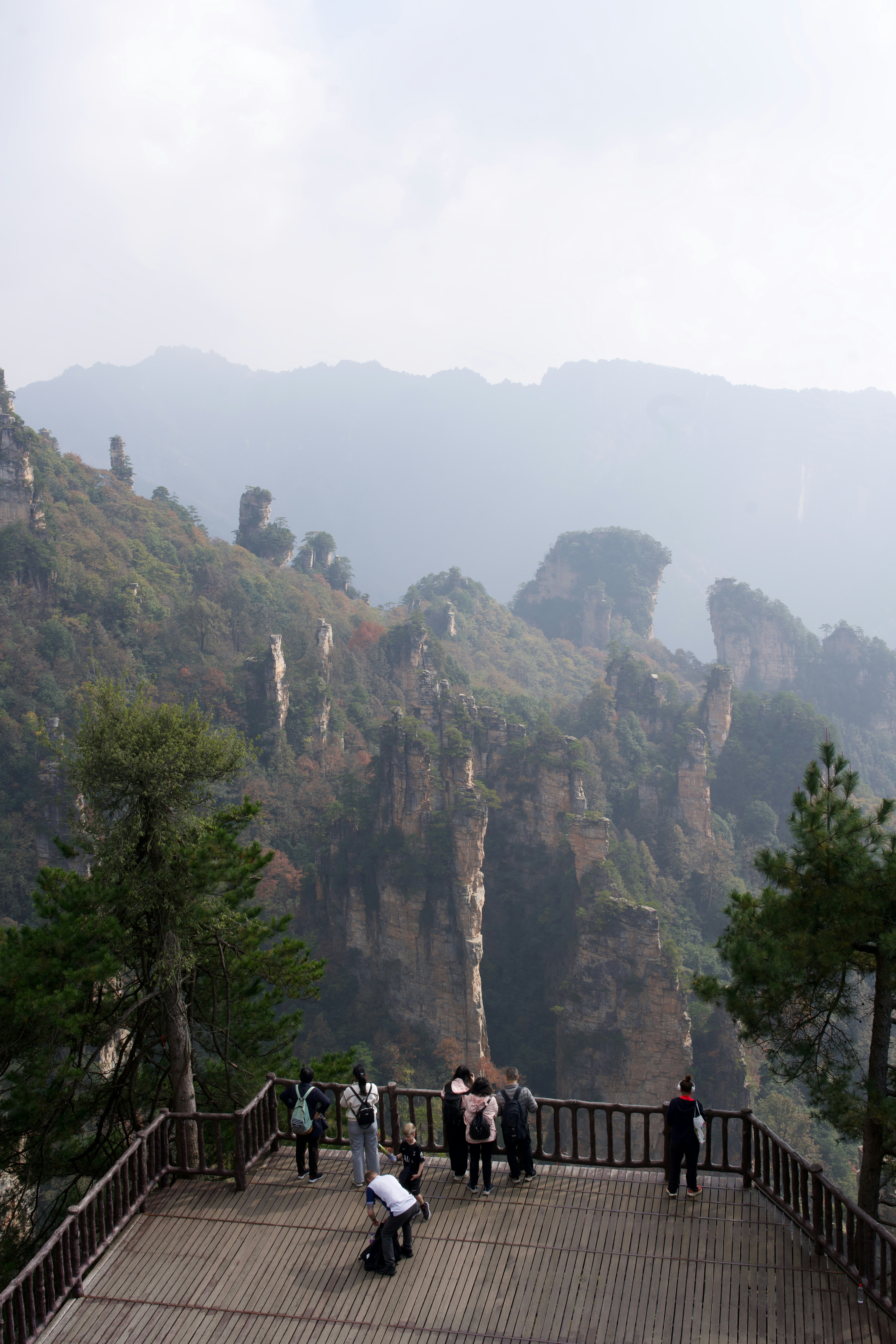 Tourists on viewing platform overlooking misty mountain peaks