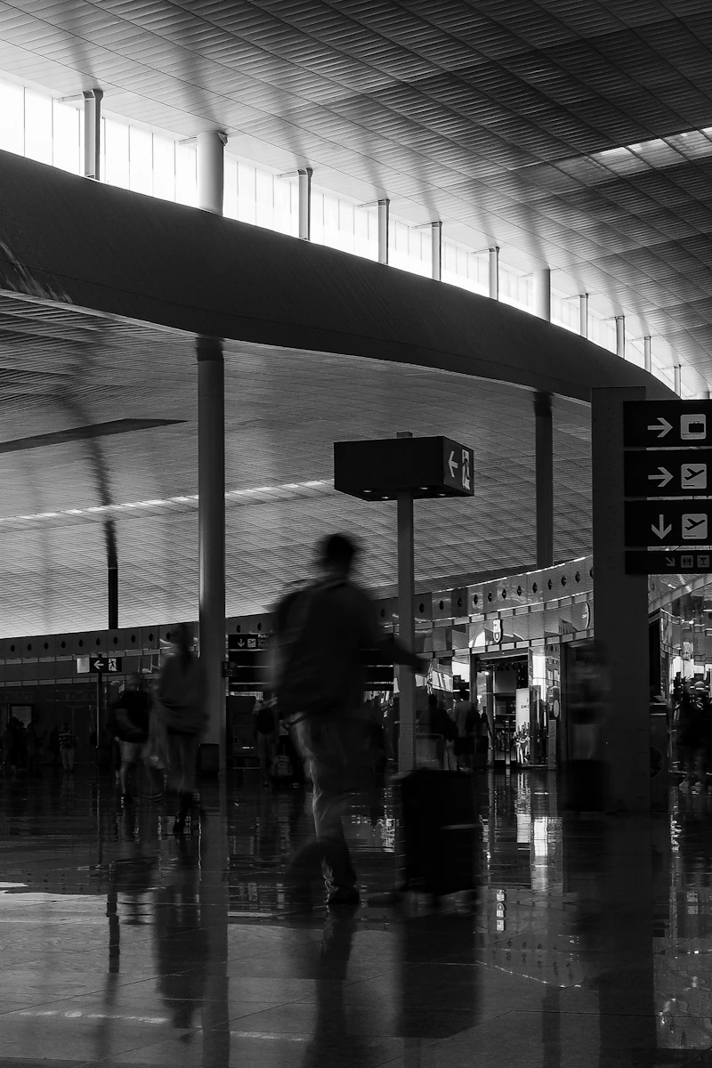 Person walking with a suitcase through a busy airport terminal.
