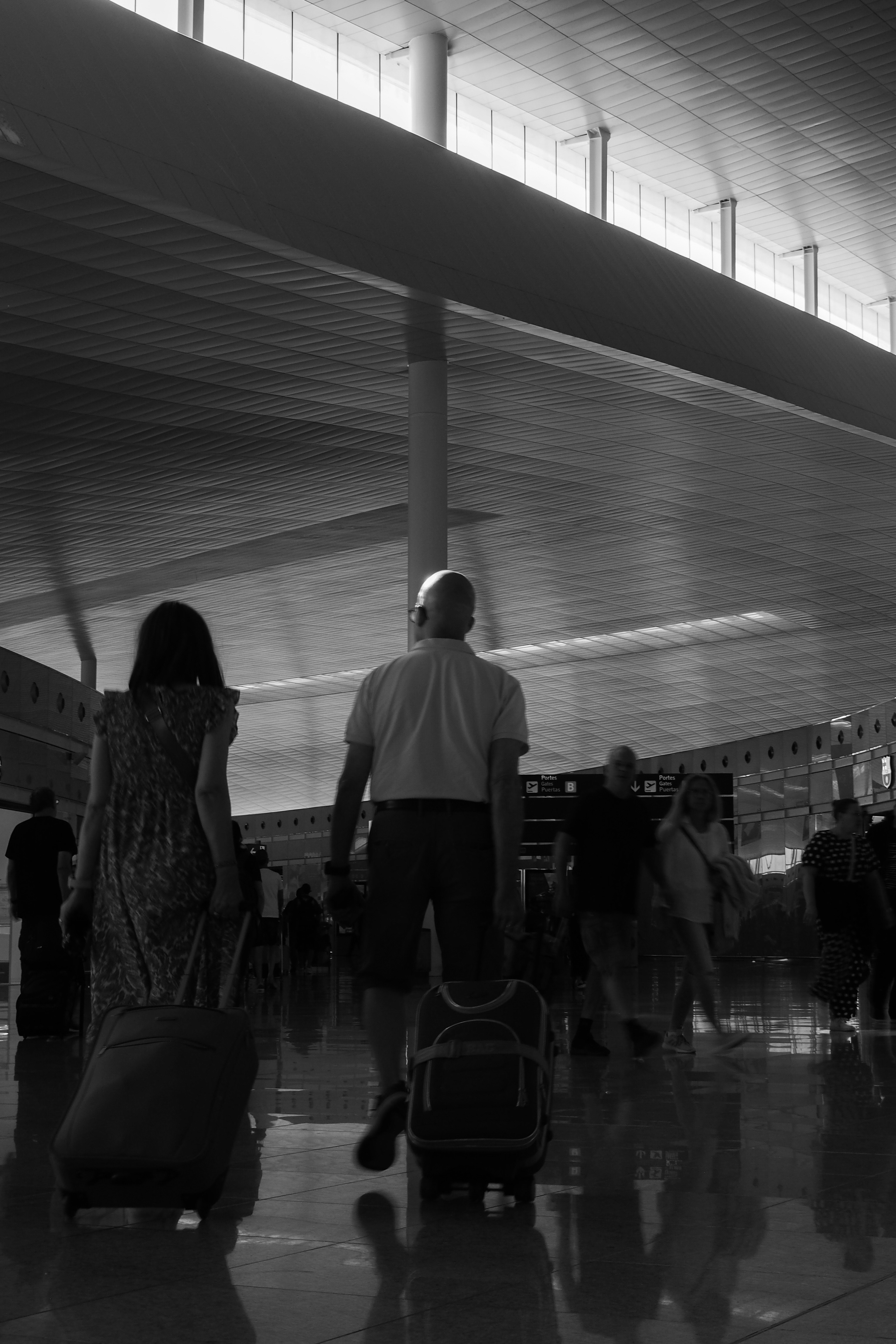 People with luggage walking in a modern airport terminal.
