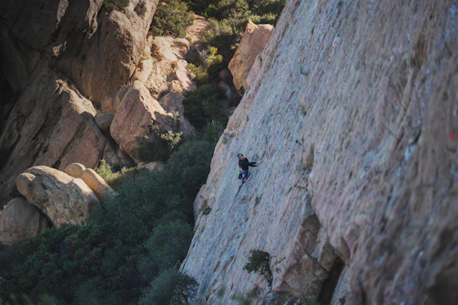 A lone climber scales a sheer rock face.