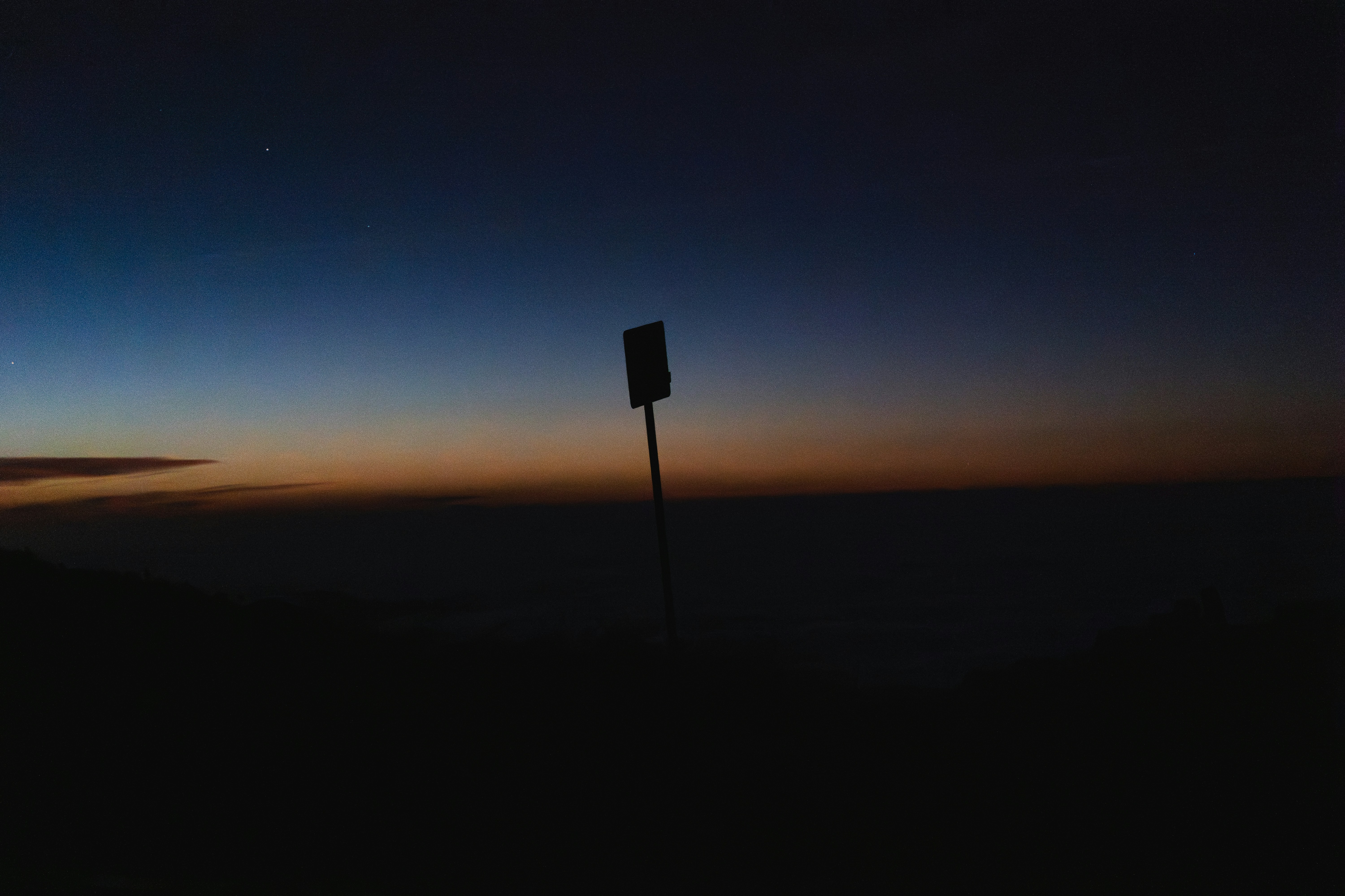 Horizonte escuro com um único marco ao anoitecer.